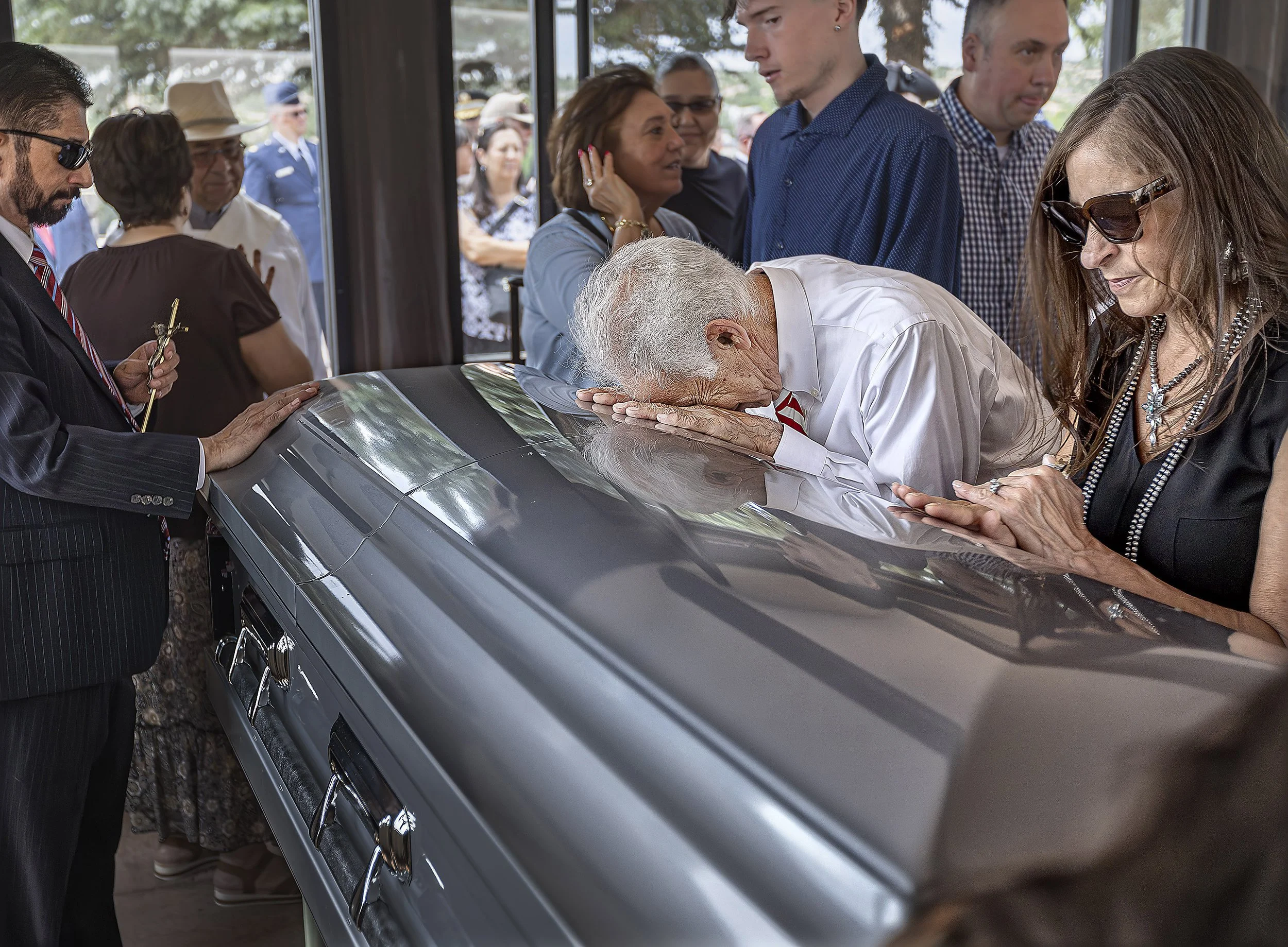  Philip Trujillo, center, rests his head on a casket holding the remains of his cousin during a funeral ceremony on Friday, July 26, 2024 at the Santa Fe National Cemetery for Pvt. Manuel Trujillo who was finally laid to rest after his remains were i