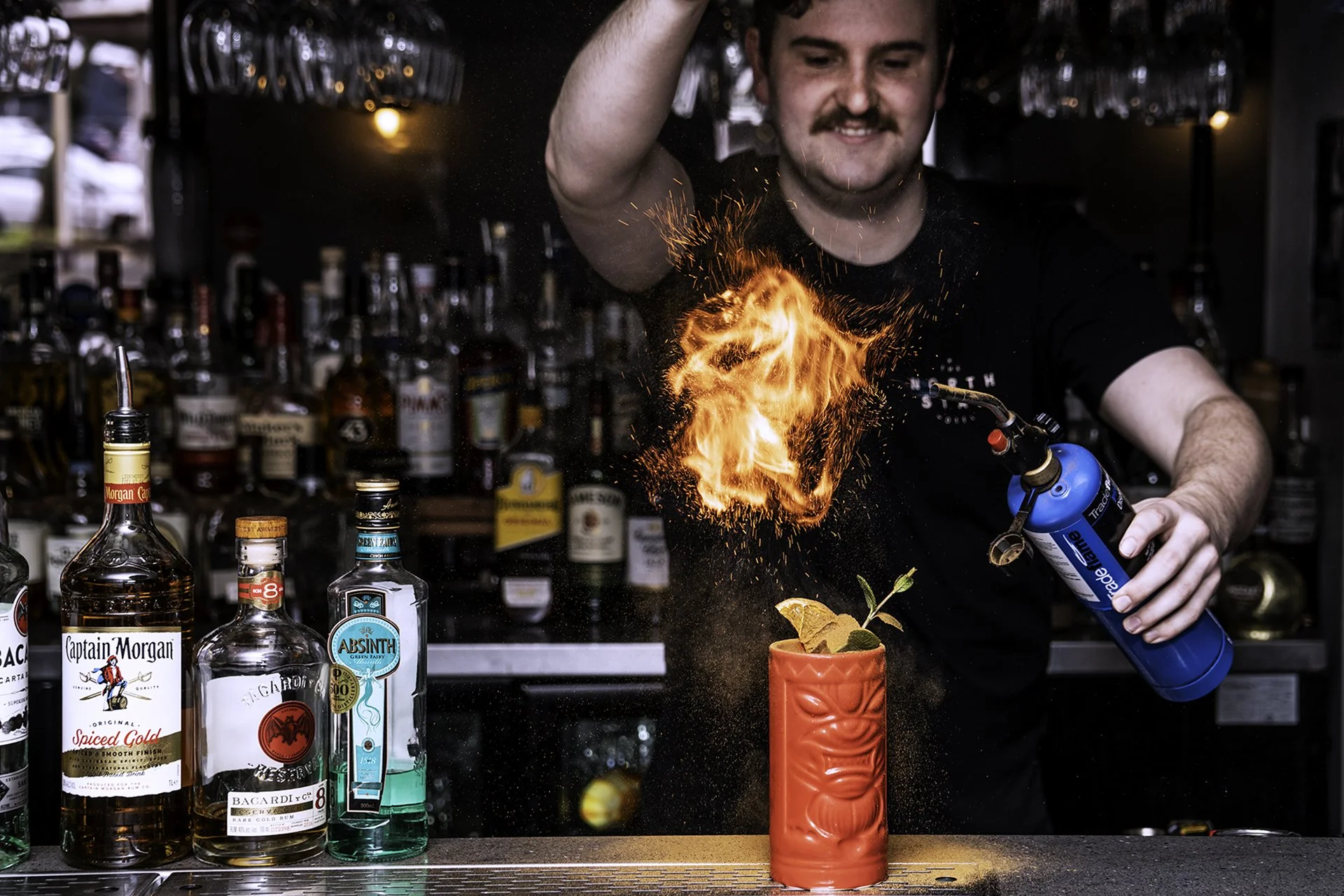 Bartender creating a flaming cocktail behind the bar at The North Star Hotel.