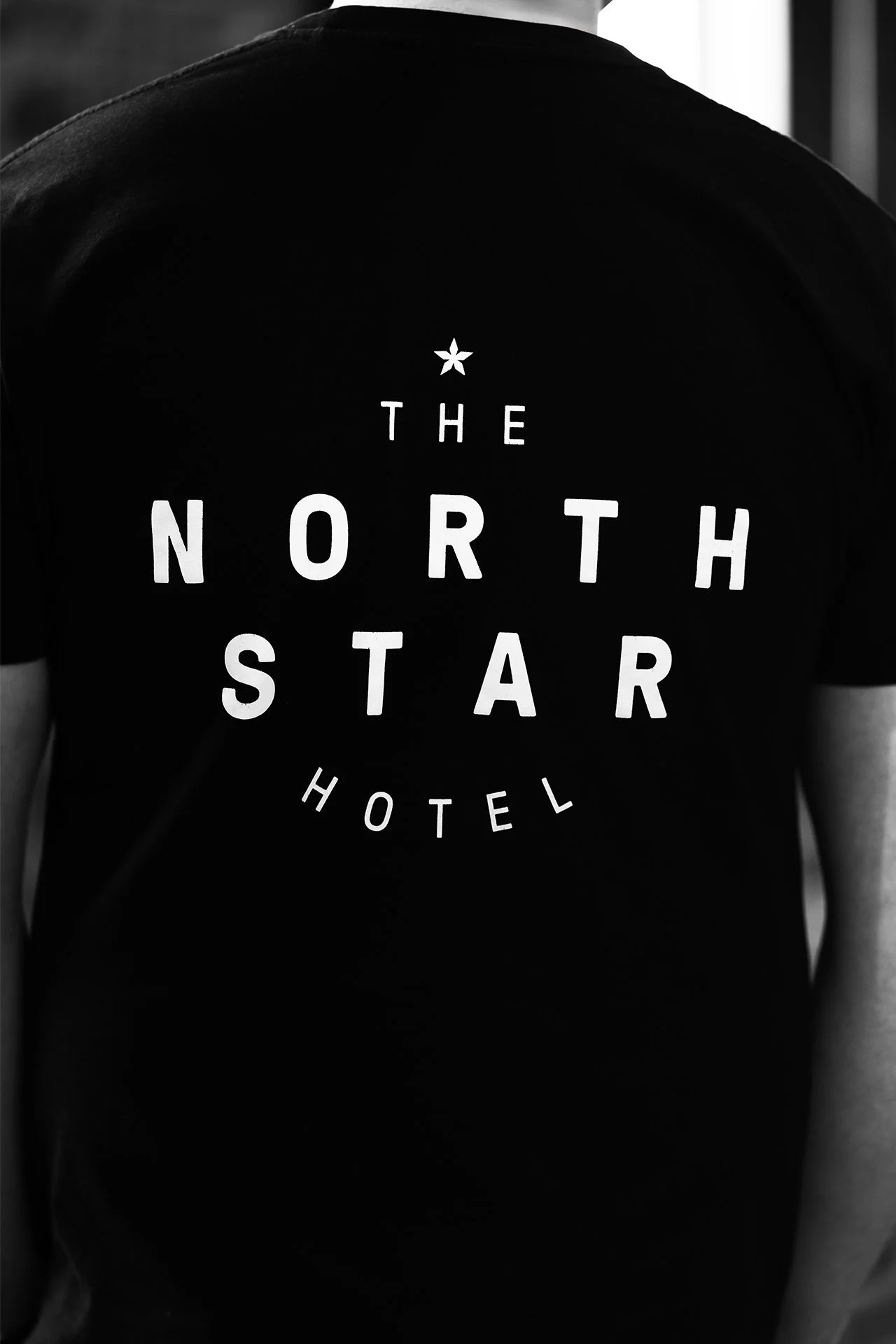 Black T-shirt with white text that reads 'The North Star Hotel' and a star graphic at the top center.