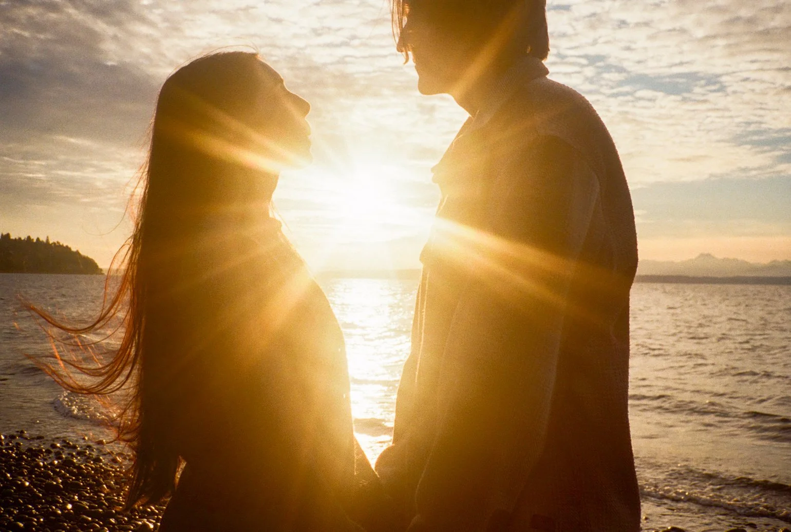 couple on film enegagement at the beach with a sunset holding hands