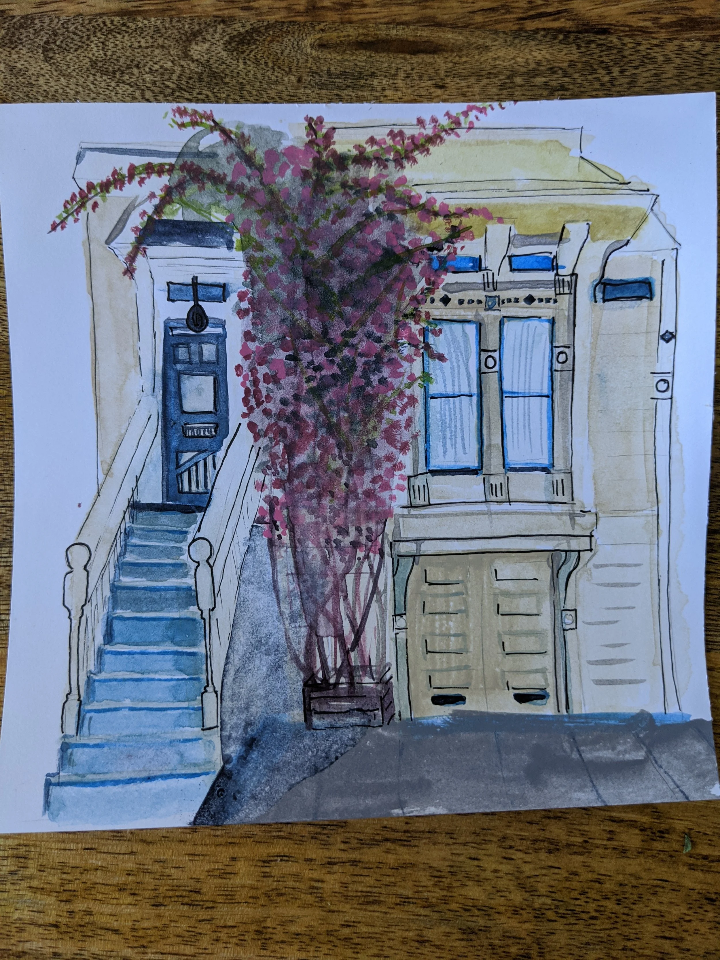 Watercolor painting of a house's front with yellow facade, blue bicycles on the porch, a pink flowering tree beside the stairs, and a garage door at the bottom.