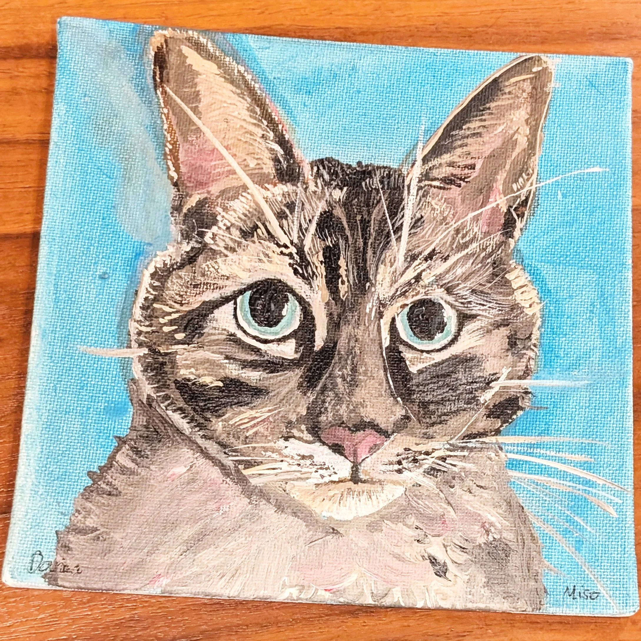 Painting of a cat with light blue eyes, pink nose, and tabby fur, set against a bright blue background.