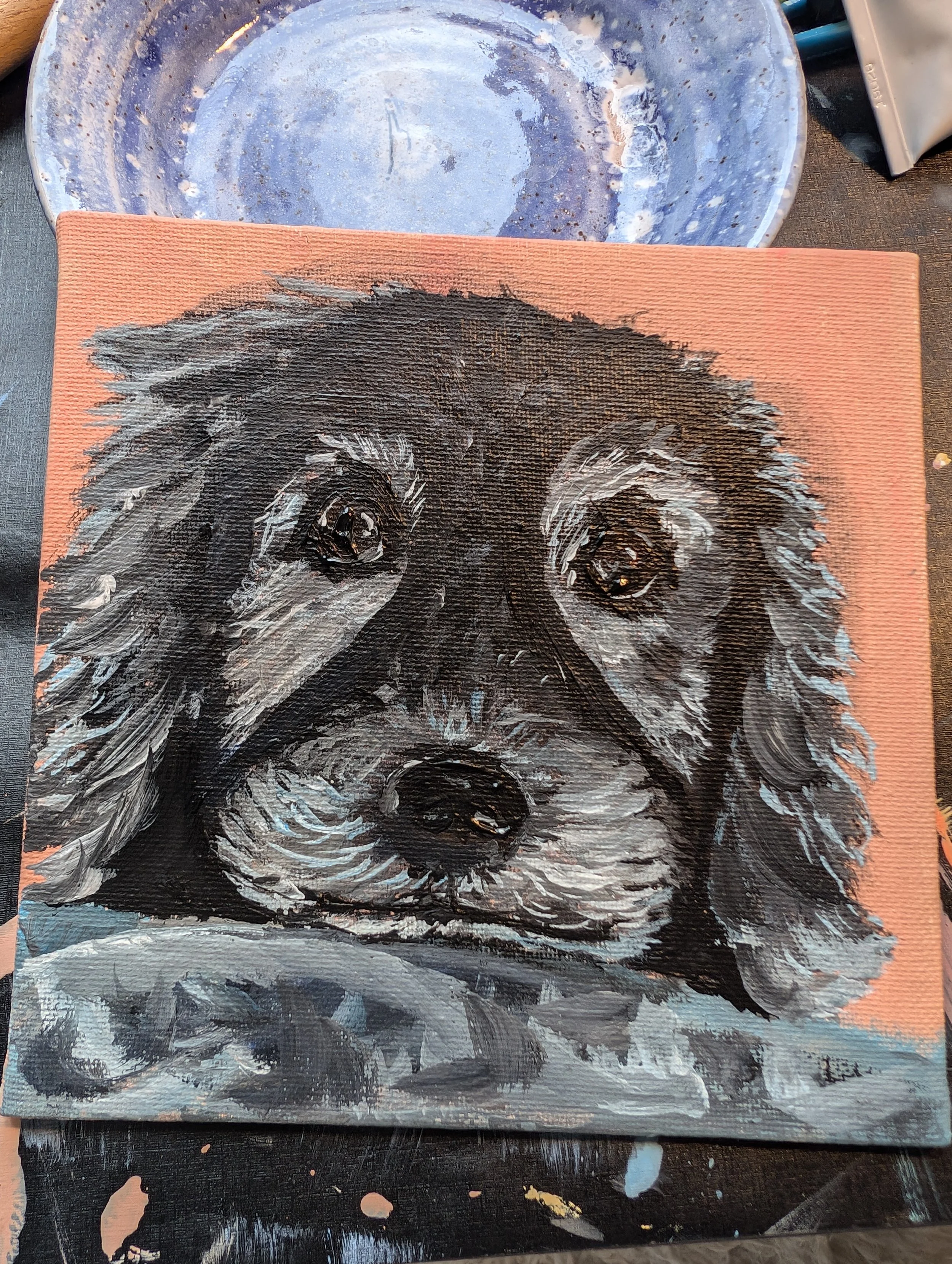 A painting of a black and white dog with long fur on a pink canvas.