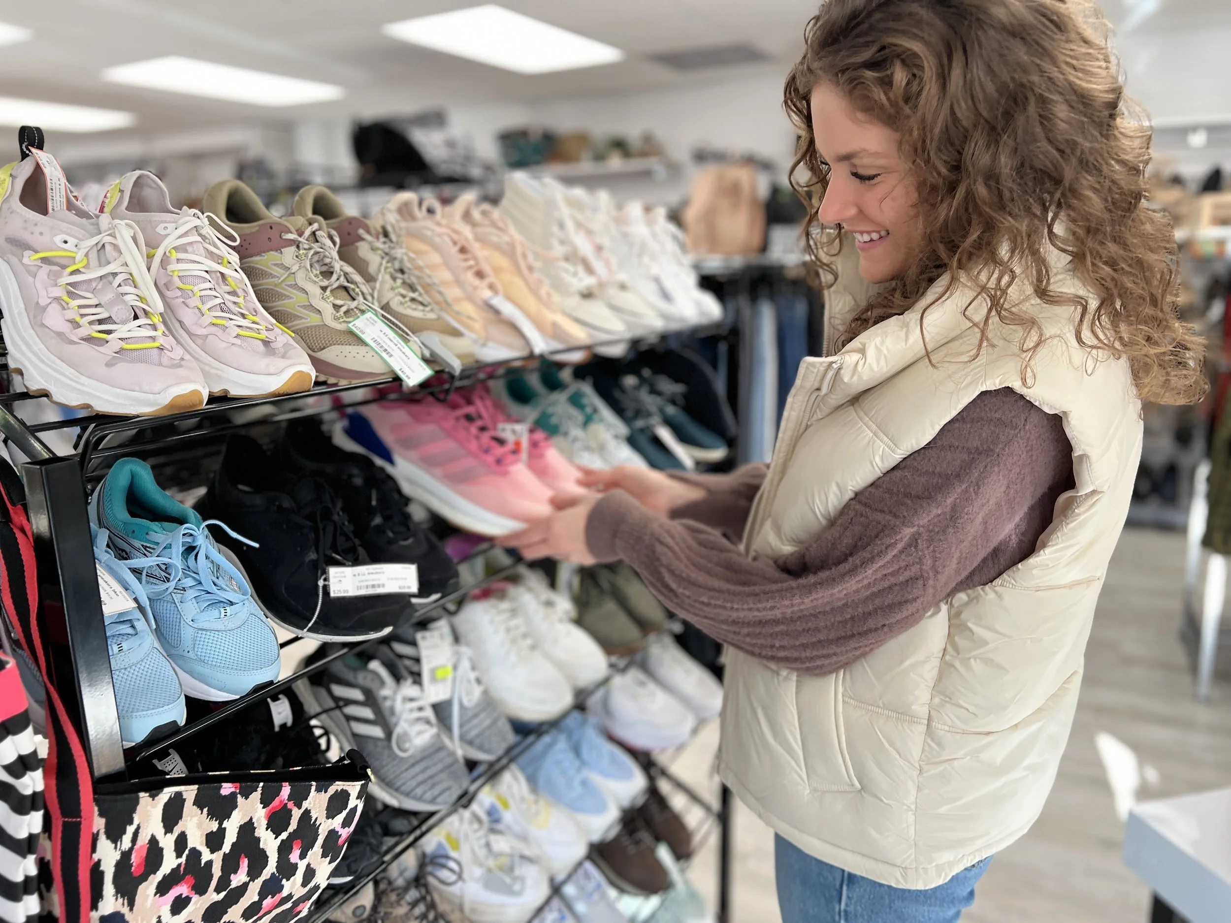 Woman shopping a rack of new and used sneakers