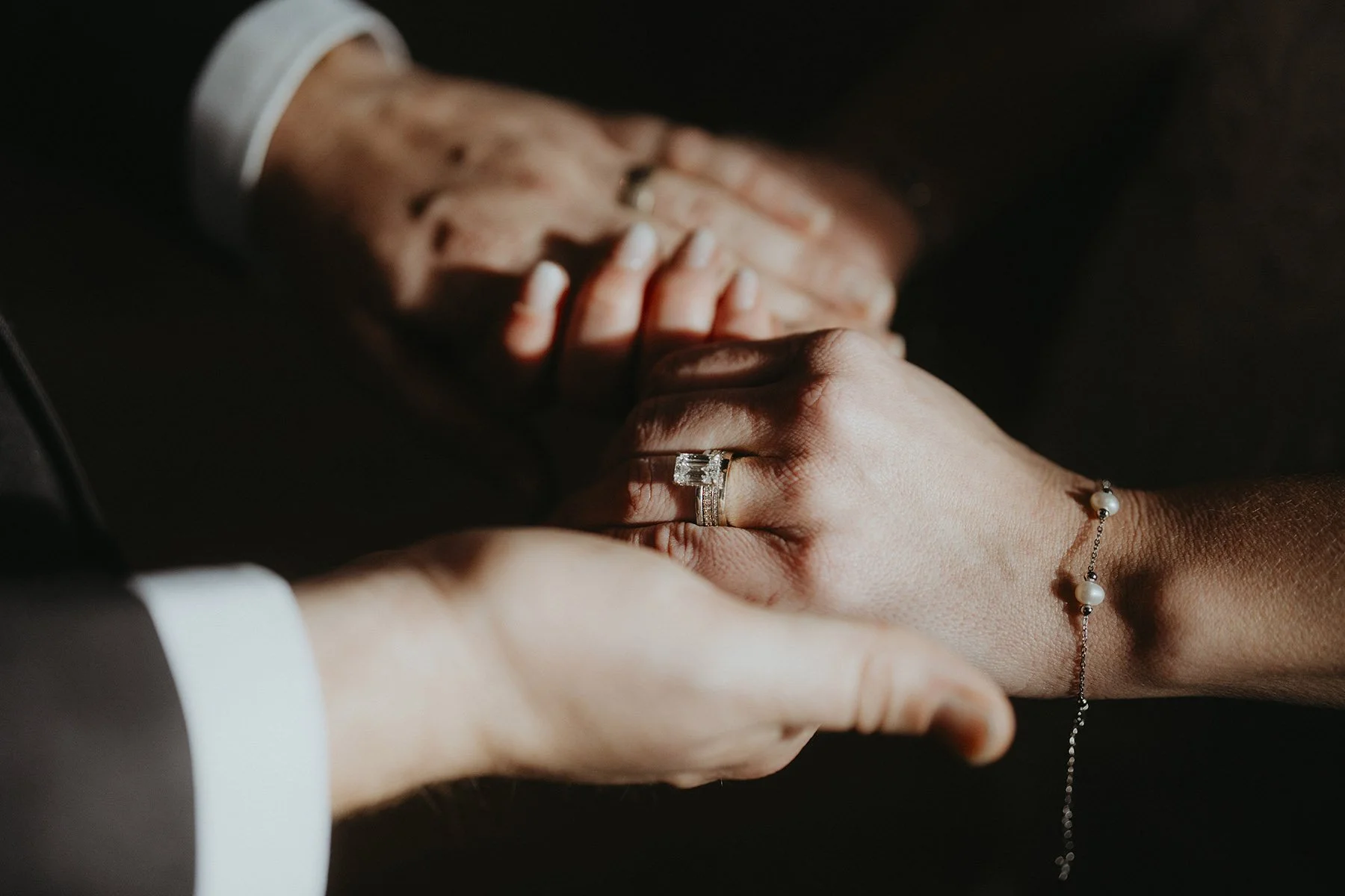 soft light couple holding hands with their wedding bands