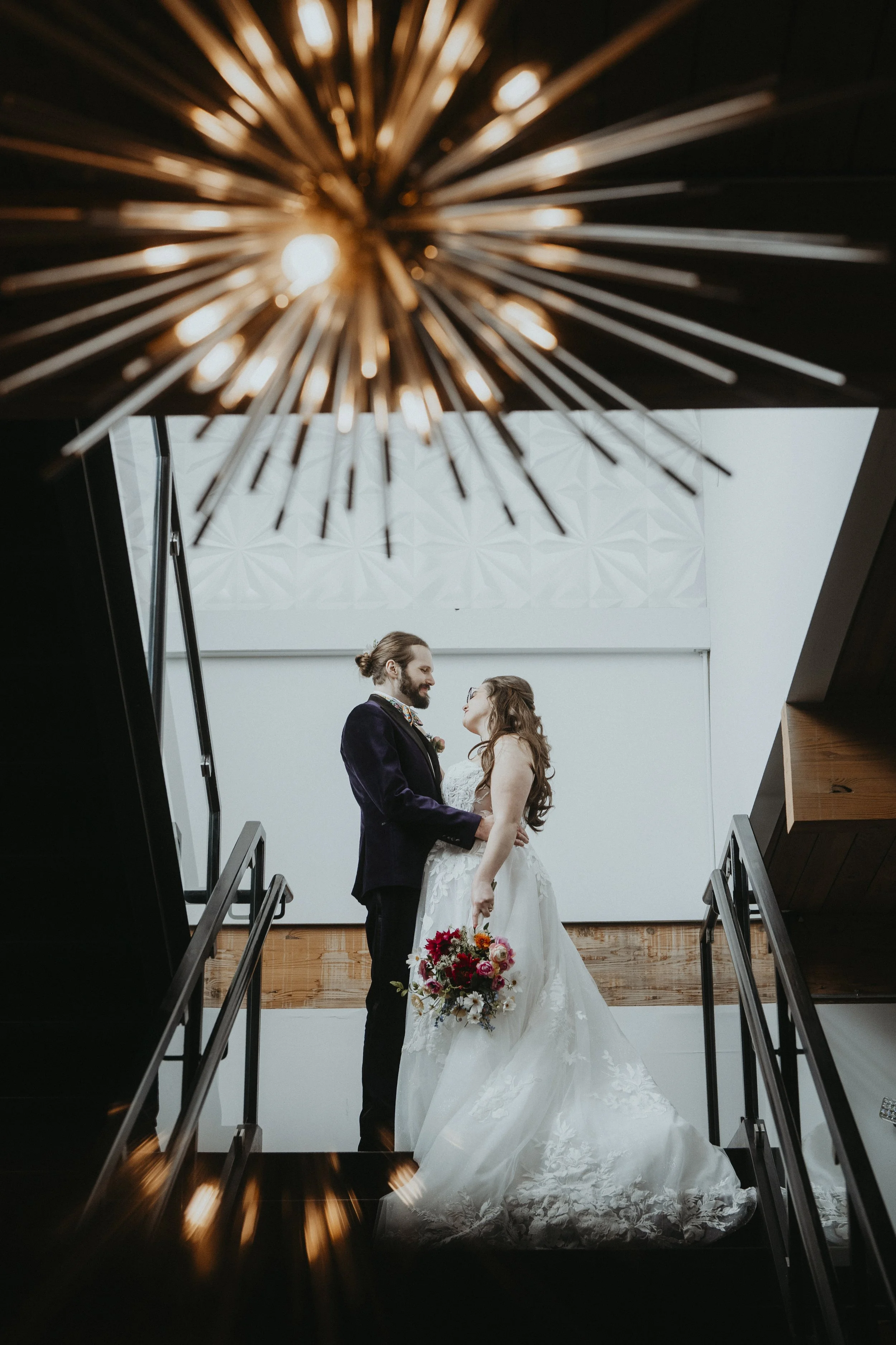 Bride and groom pause at the top of a staircase for a romantic moment.