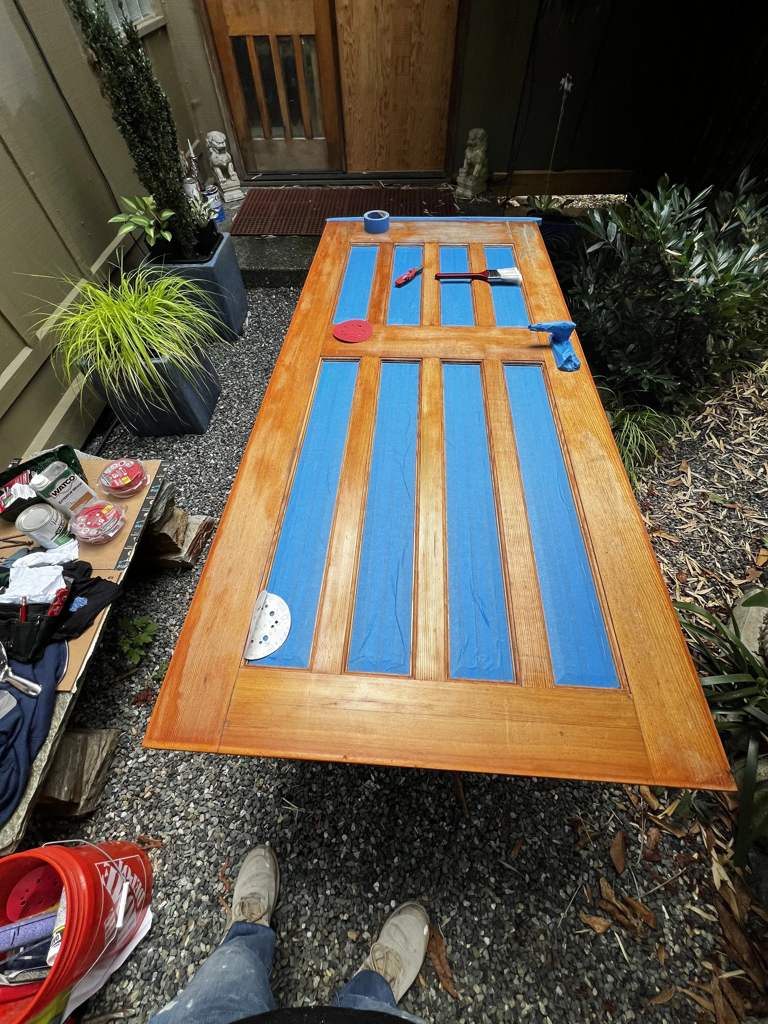 Seattle handyman performing wood door restoration on 20-year-old exterior doors with natural stain
