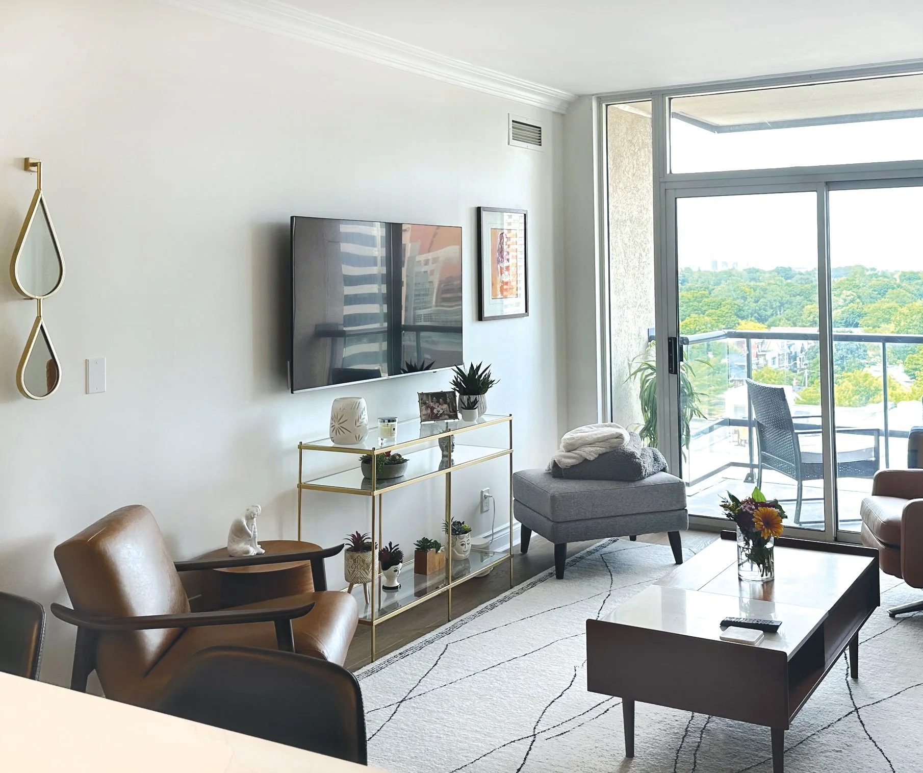 Moved artwork from office, hung to right of TV. Colours tie in with warmtones in room • Added tear drop mirror to reflect light, gold matches glass table. • Moved Marilyn Monroe Art to dining room. • Styled existing accessories. •  Moved recliner ch