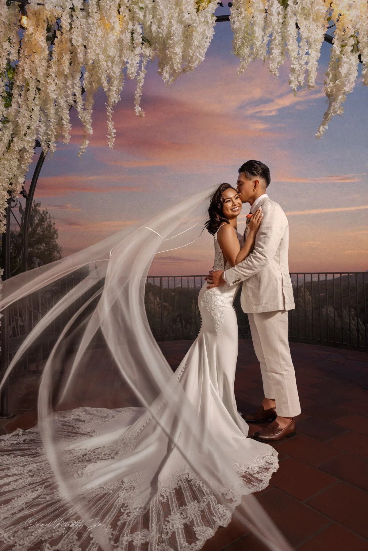 Beautiful Bride and Groom on the terrace as her veil whips at Padua Hills Theatre.