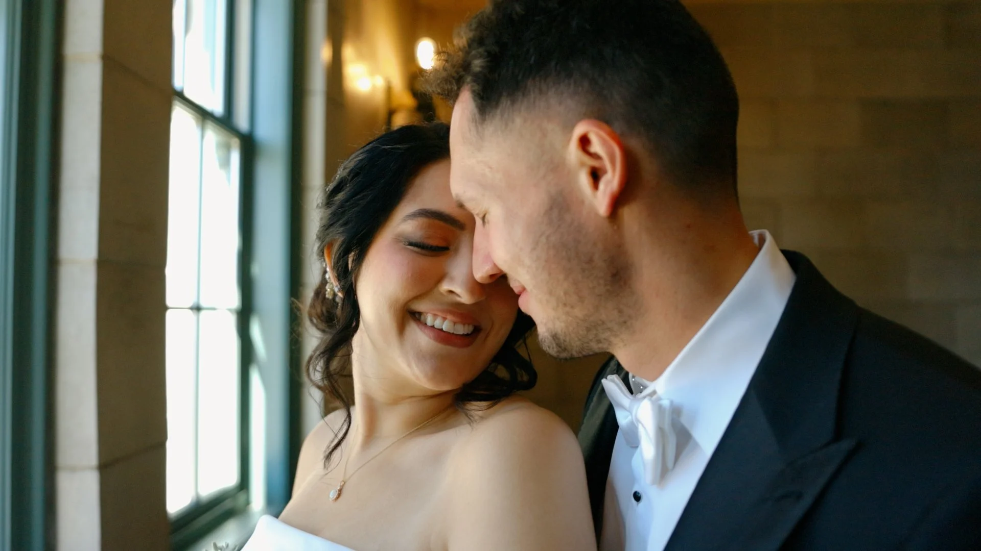 “Breanna and Jesse share an intimate moment by a sunlit window on their wedding day in Joliet, Illinois.”