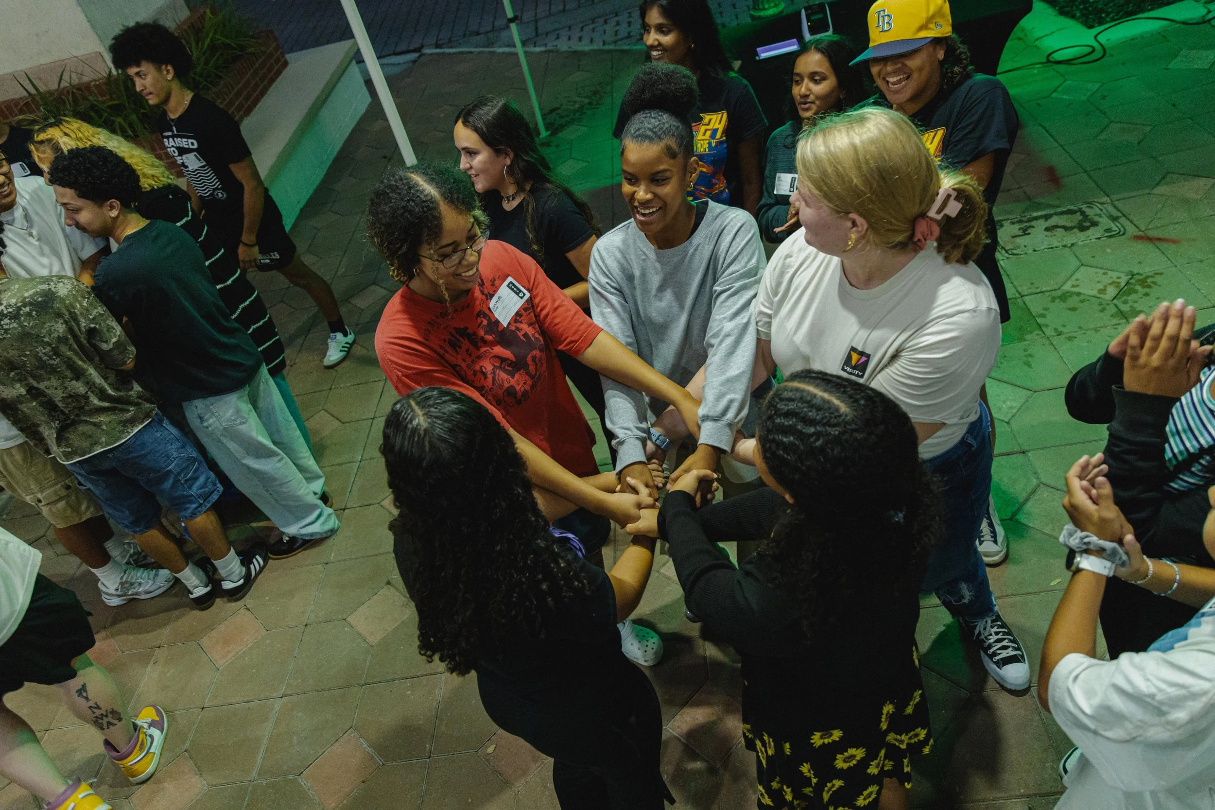 Group of diverse young women standing in a circle, holding hands, smiling and having fun.