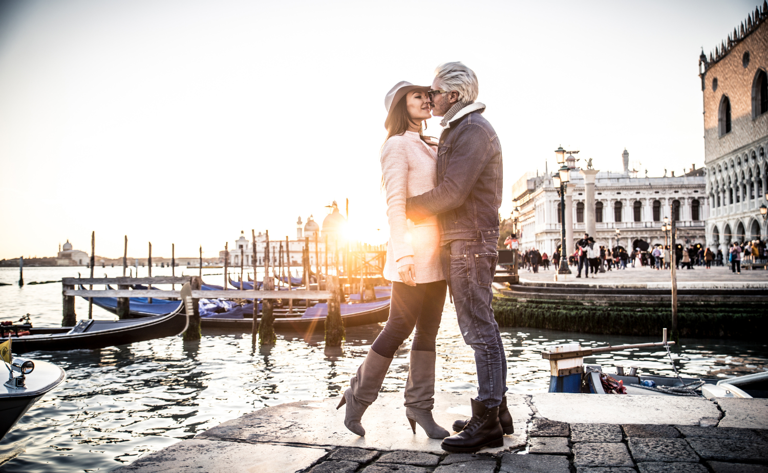 A couple enjoys coffee together on a balcony overlooking a historic Italian city in the morning light.