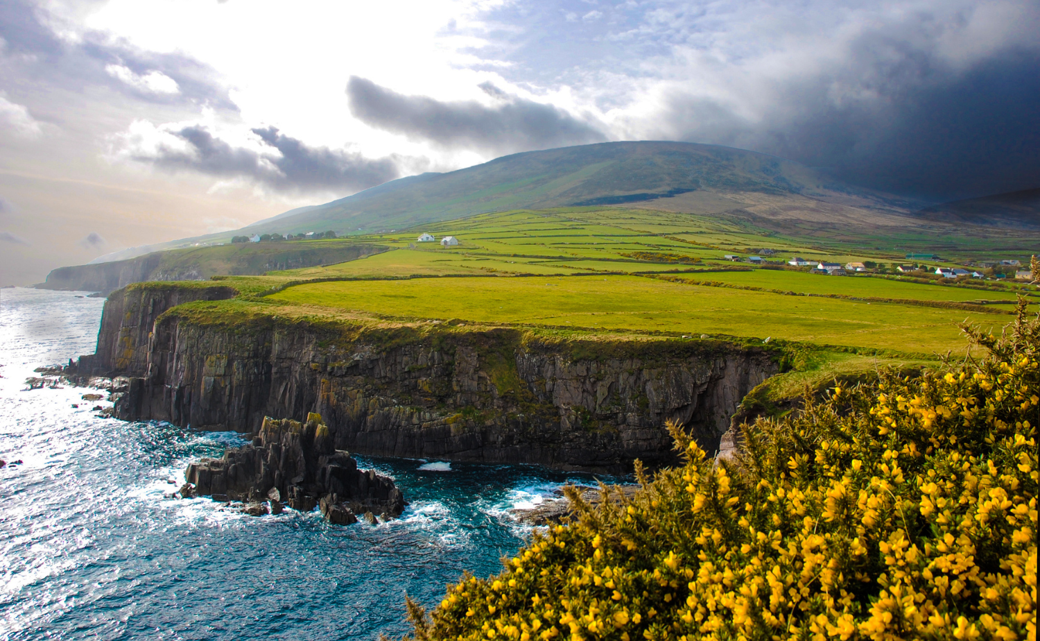 Rugged coastal cliffs in Northern Ireland overlooking the Atlantic Ocean under a dramatic sky.