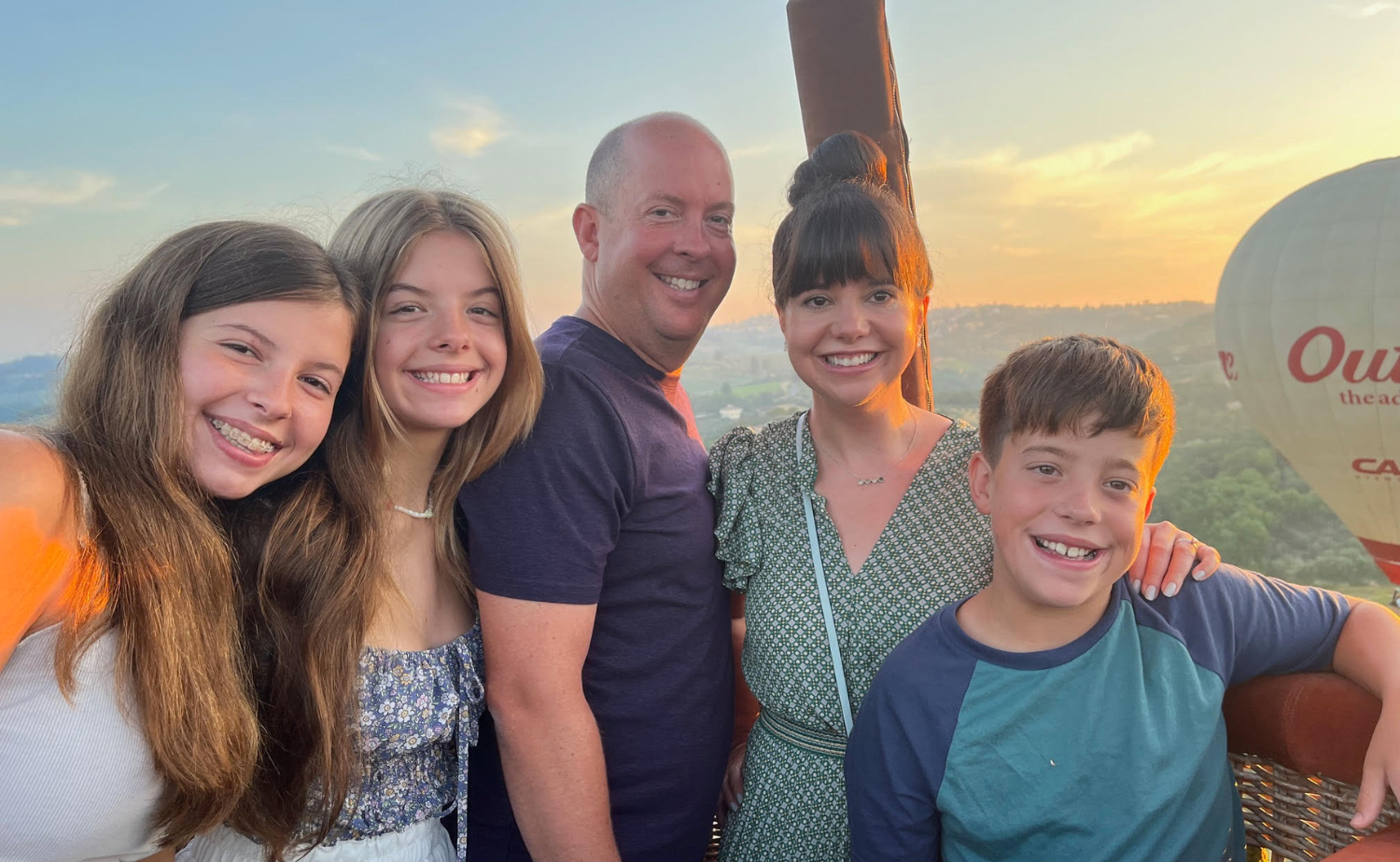 Legg family smiling in a hot air balloon basket over the Tuscan countryside at sunset