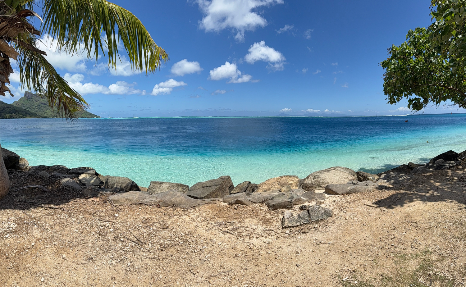 Panoramic view of a clear blue lagoon with tropical shoreline and distant islands, captured during a Castaway Destinations client trip to Tahiti.
