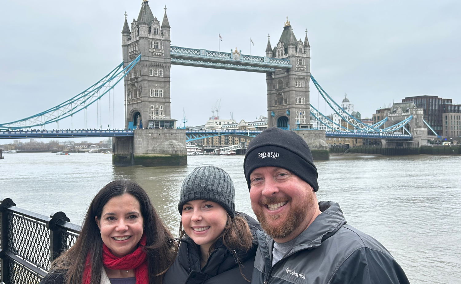 Family posing along the Thames with Tower Bridge visible in the background.