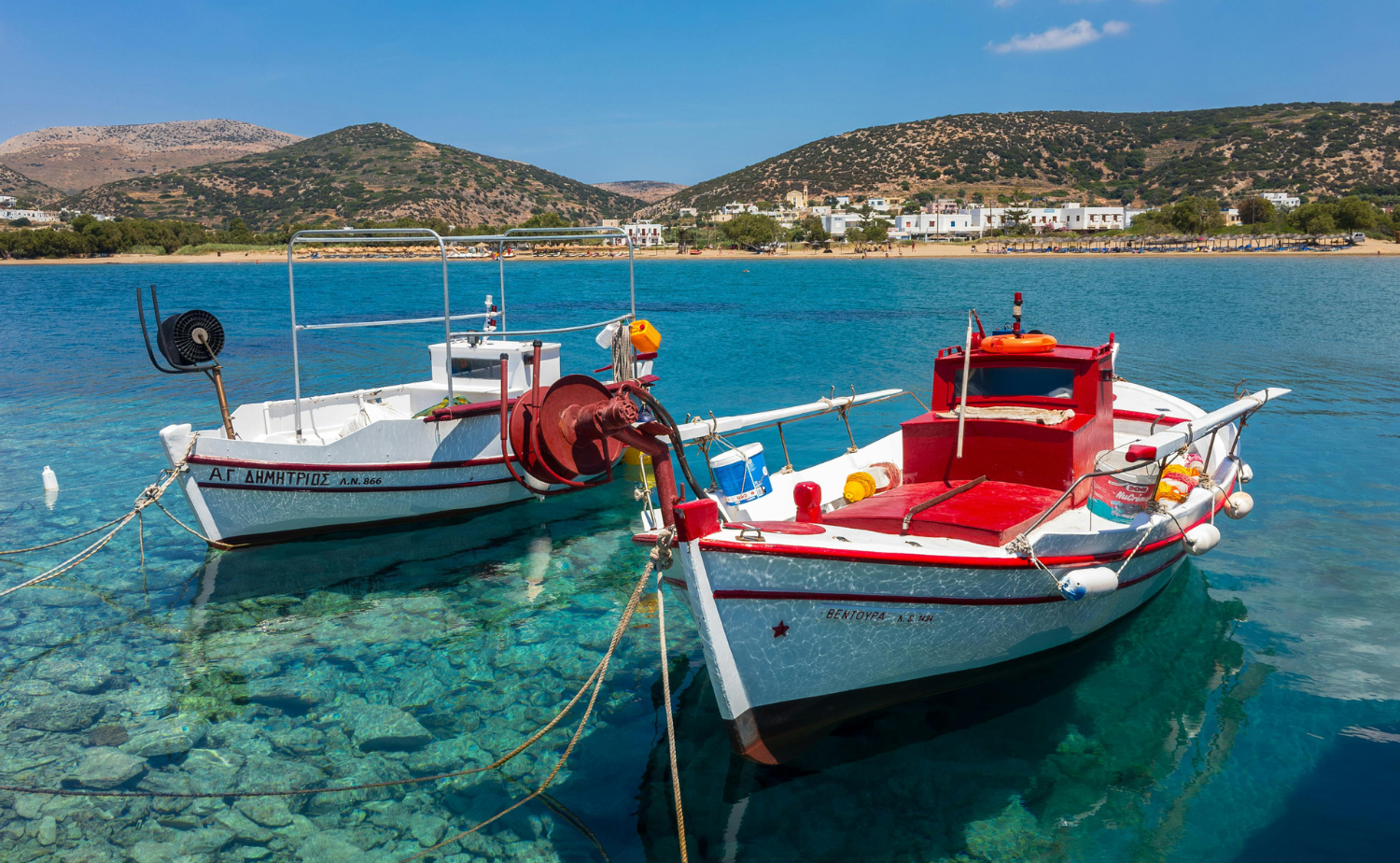 Colorful traditional fishing boats floating in clear turquoise water off Syros, Greece
