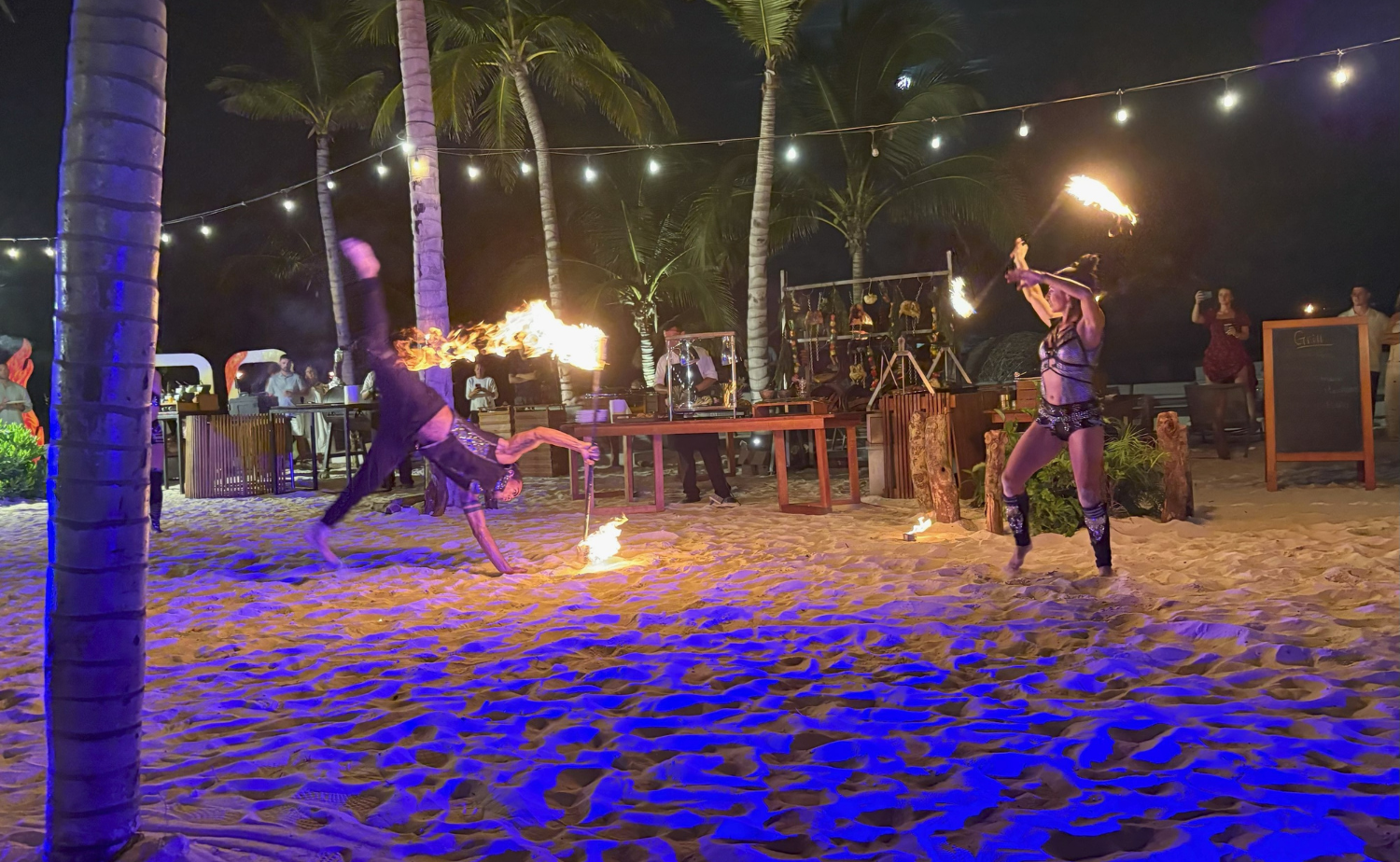 Fire dancers performing on the beach at night during an all-inclusive resort show in Playa del Carmen, Mexico.