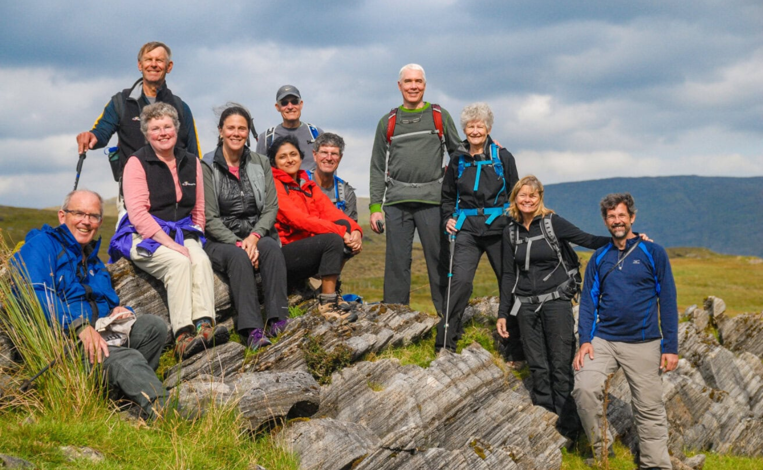 A small group of travelers hiking together across an open Irish landscape with mountains in the background.