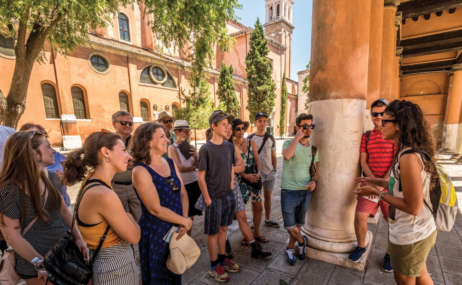 Small group of travelers listening to a local guide during a walking tour in Venice, Italy.