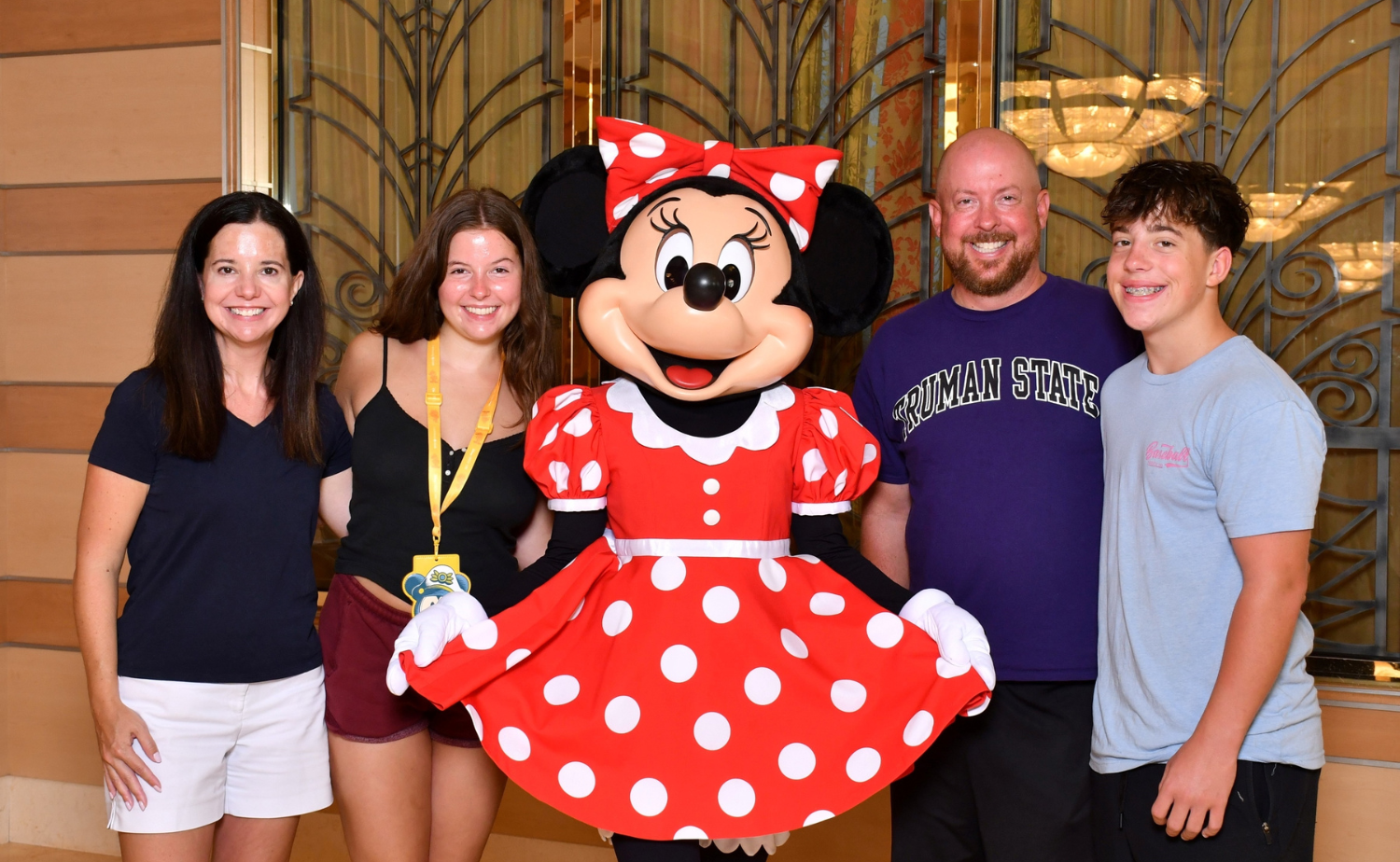 A family posing with Minnie Mouse aboard Disney Cruise Line during a high school graduation celebration trip.
