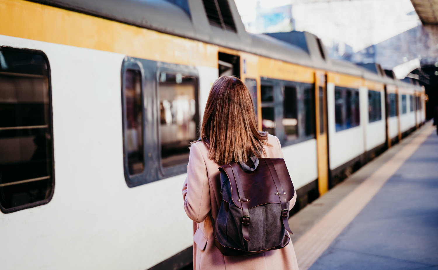 Traveler standing on a European train platform with luggage, preparing to board a train.