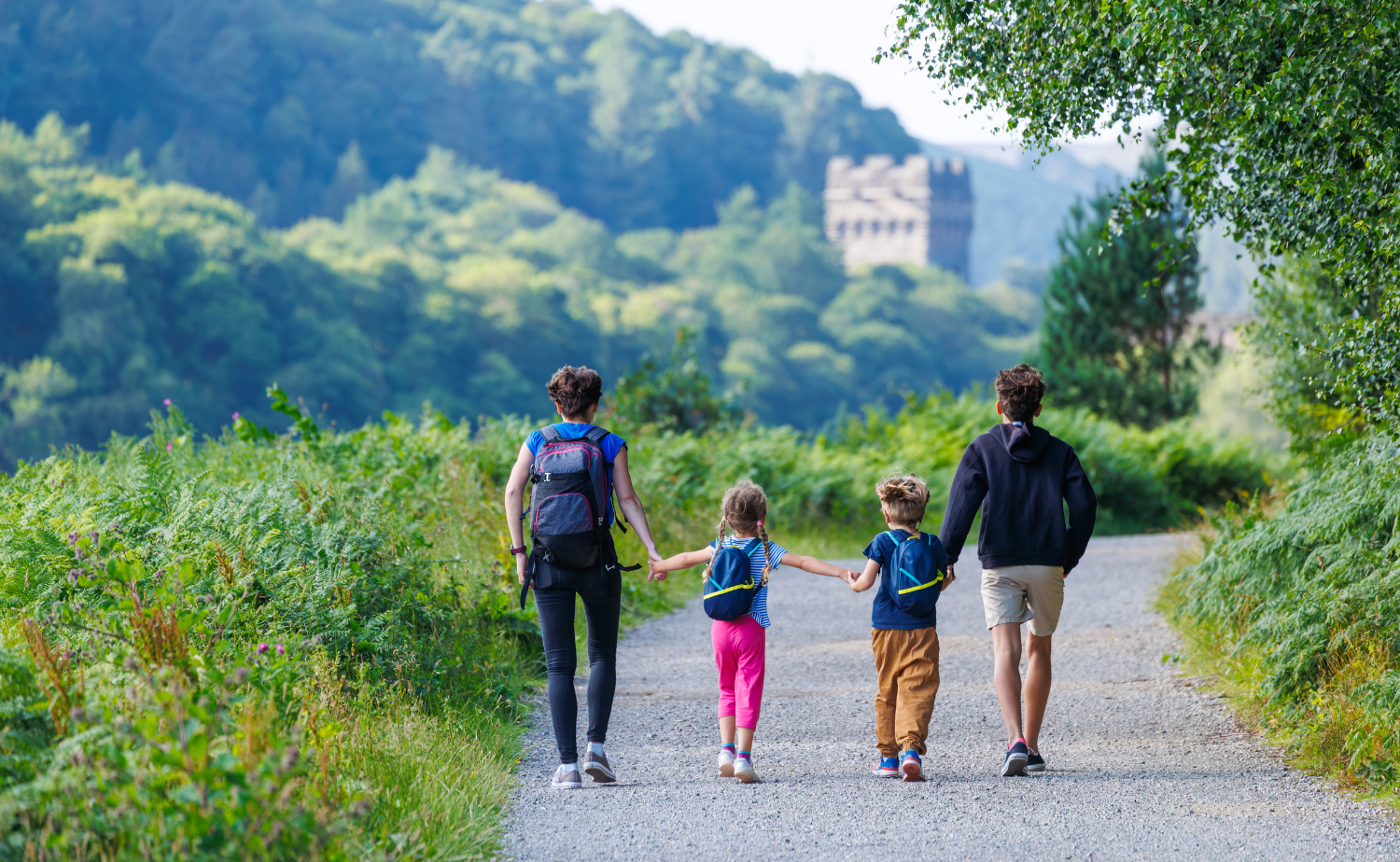 A family walking along a wooded path toward a historic site in the Irish countryside.