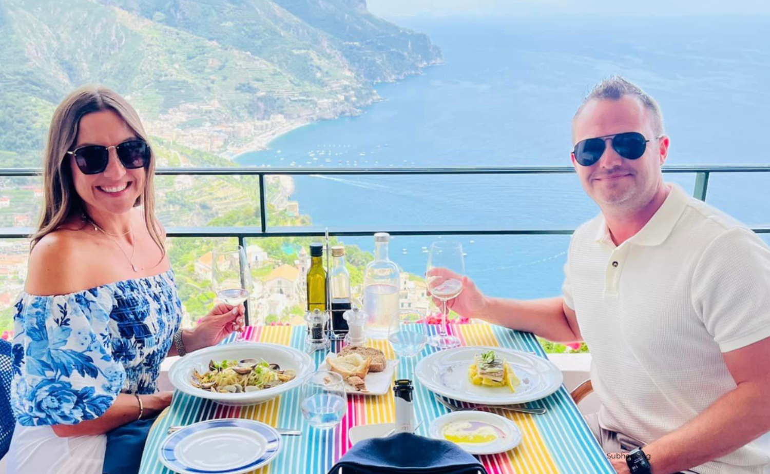 Smiling couple dining outdoors with a view over the Amalfi Coast