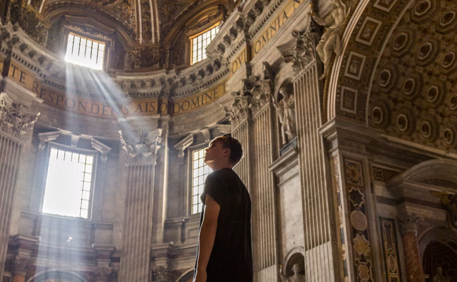 Traveler standing inside St. Peter's Basilica as sunlight streams through the historic cathedral.