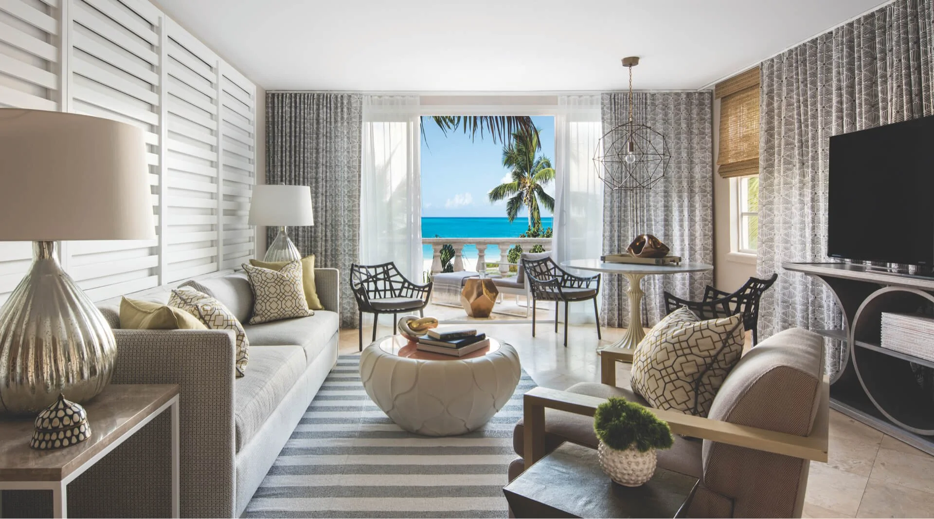 Elegant oceanfront suite with a bright living area and open balcony overlooking turquoise Caribbean waters.