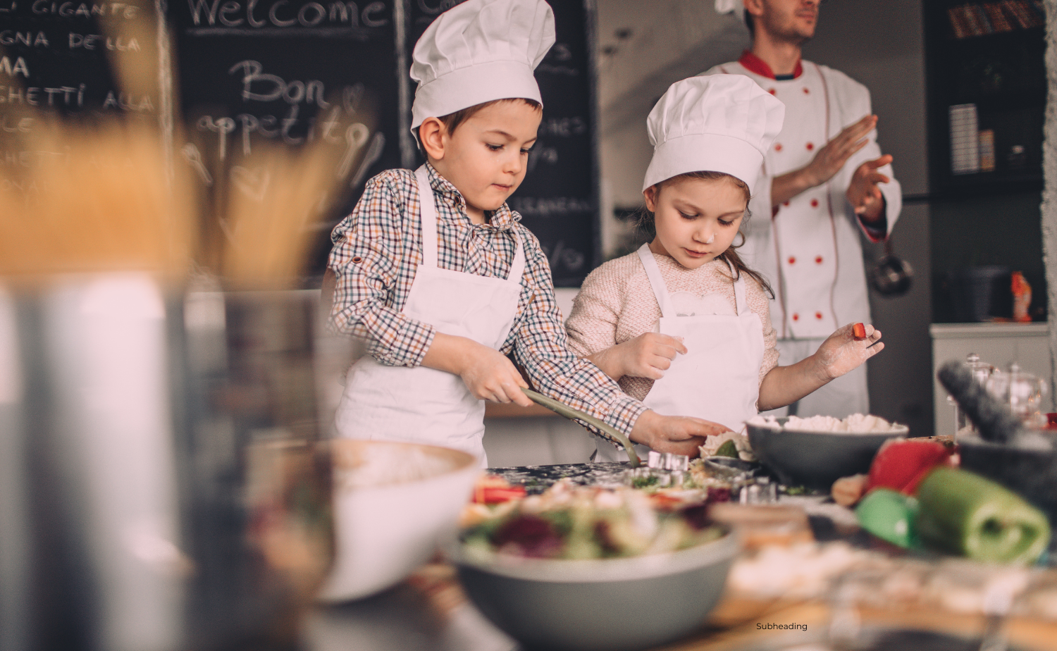 Two children wearing chef hats and aprons participate in a cooking class, mixing ingredients on a table filled with food.
