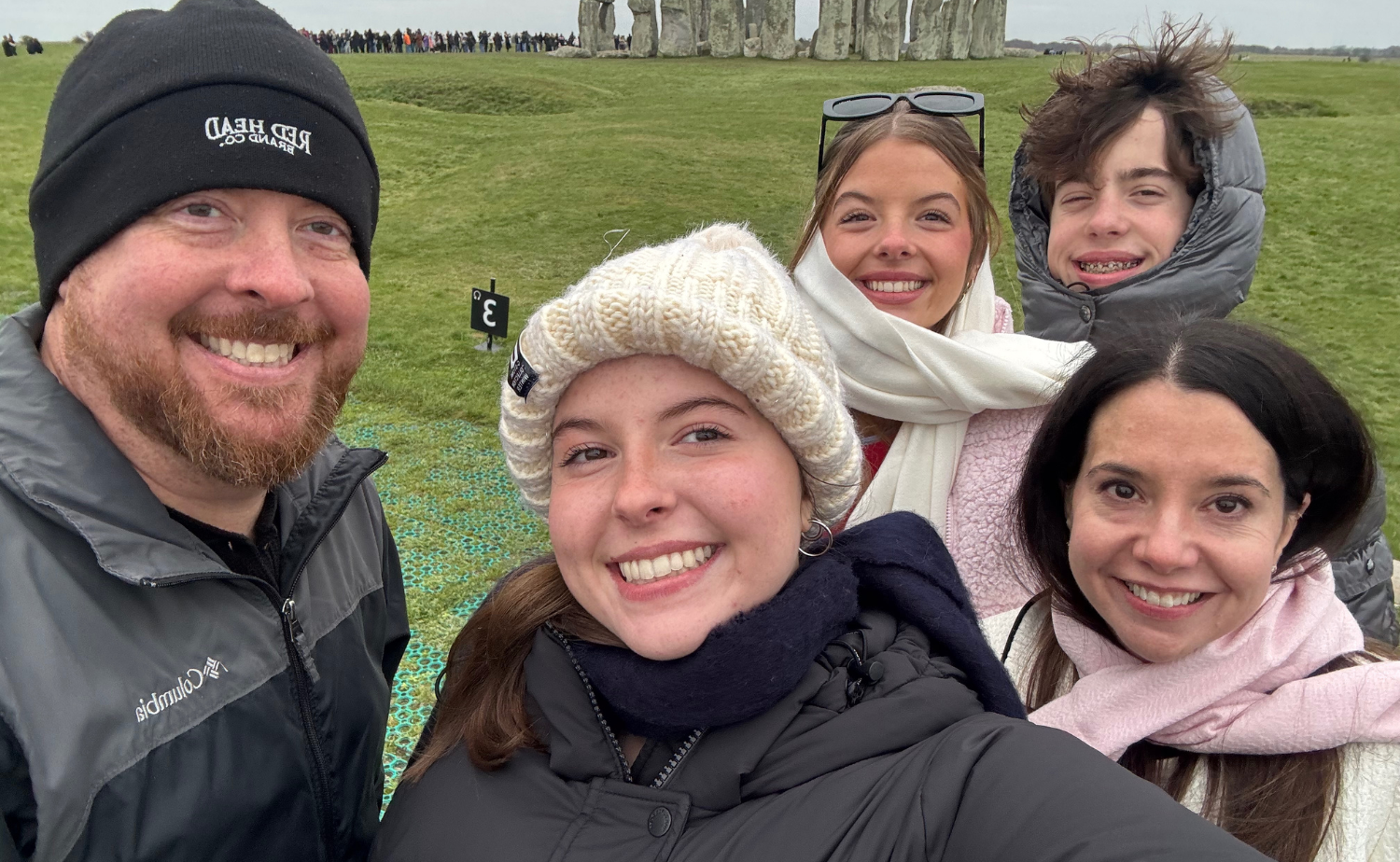 A family taking a selfie together in front of Stonehenge during a winter trip through England.