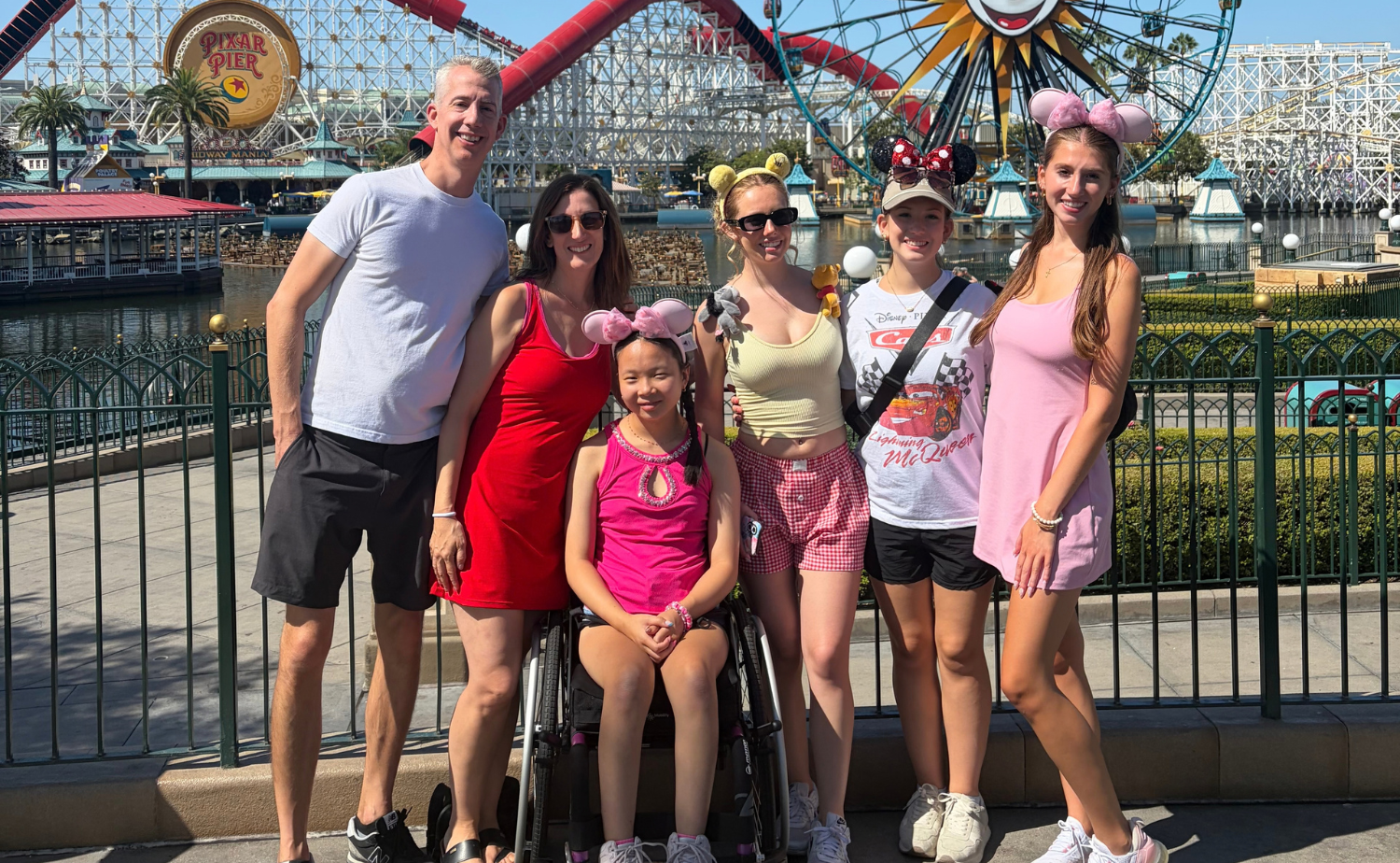 Hannah, a wheelchair user, with her family at Pixar Pier during their Disneyland vacation.