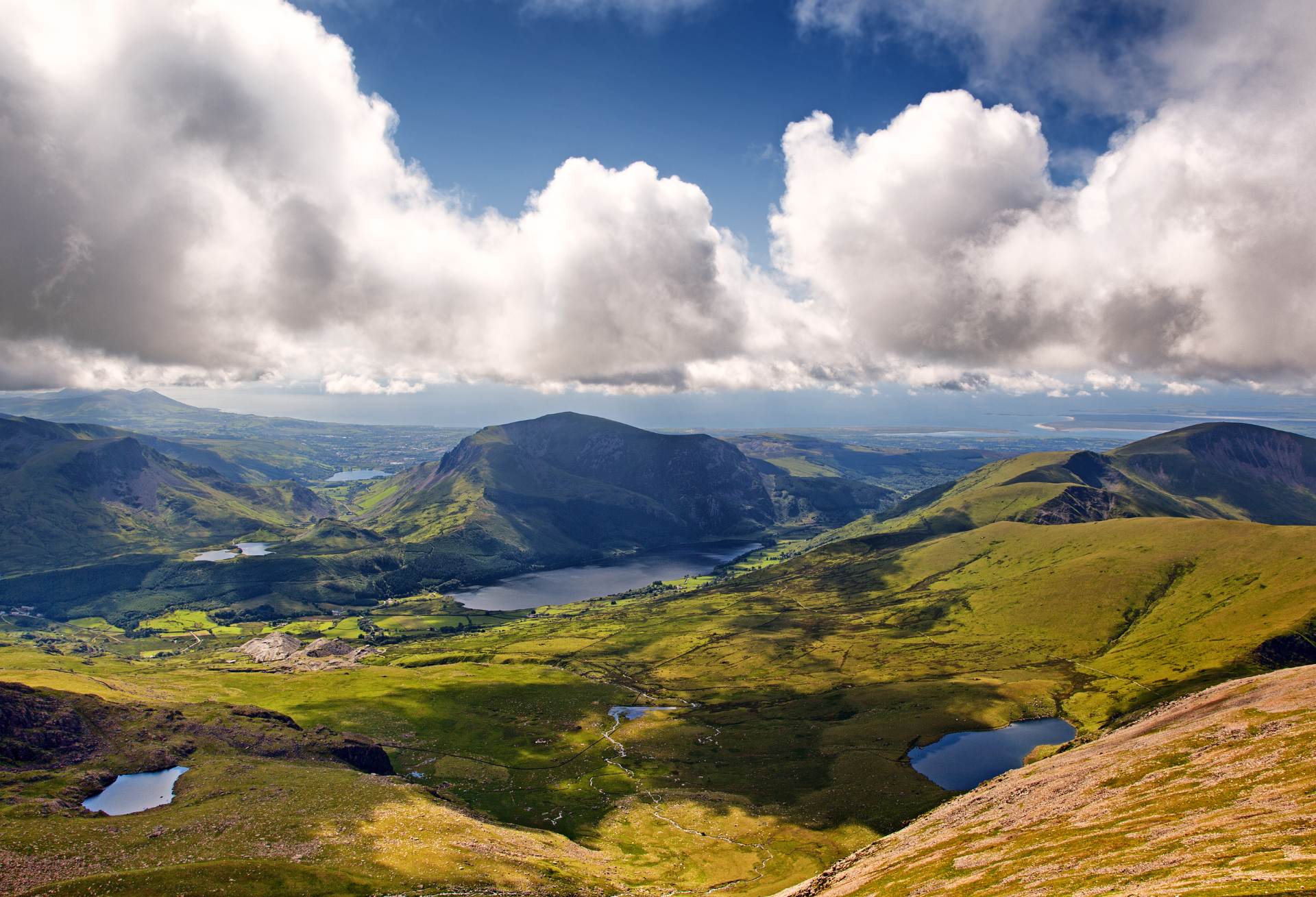 Majestic mountains, valleys, and lakes of Snowdonia National Park unfold beneath a sky of dramatic clouds.