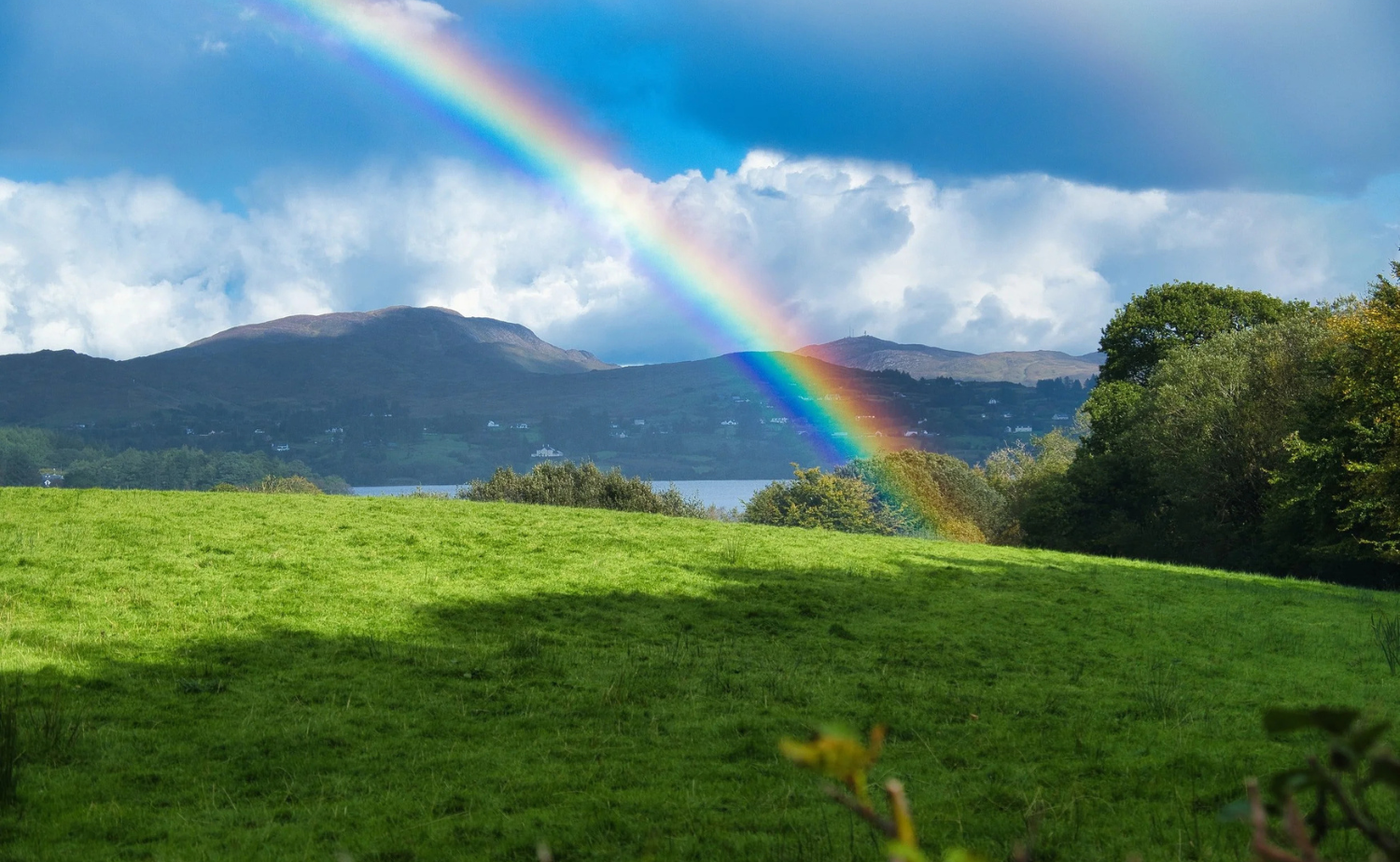 Rainbow stretching across green Irish fields after rainfall