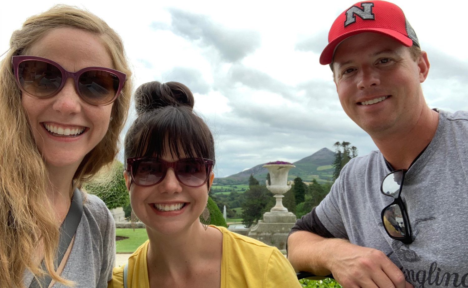 Travelers enjoying a scenic viewpoint overlooking green hills and a historic estate in Ireland.