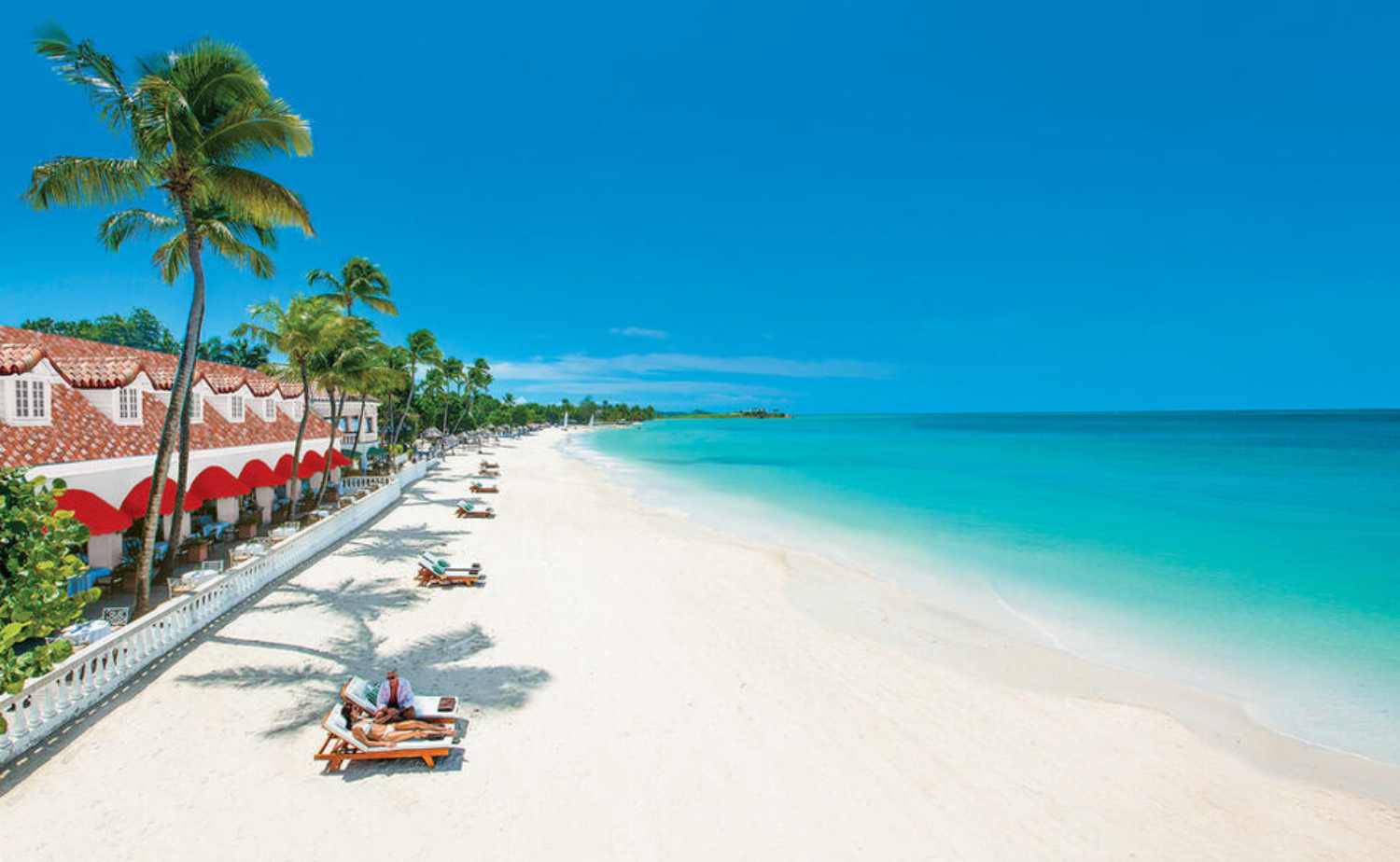 Luxury beach resort in Antigua with white sand, calm turquoise water, and oceanfront loungers.