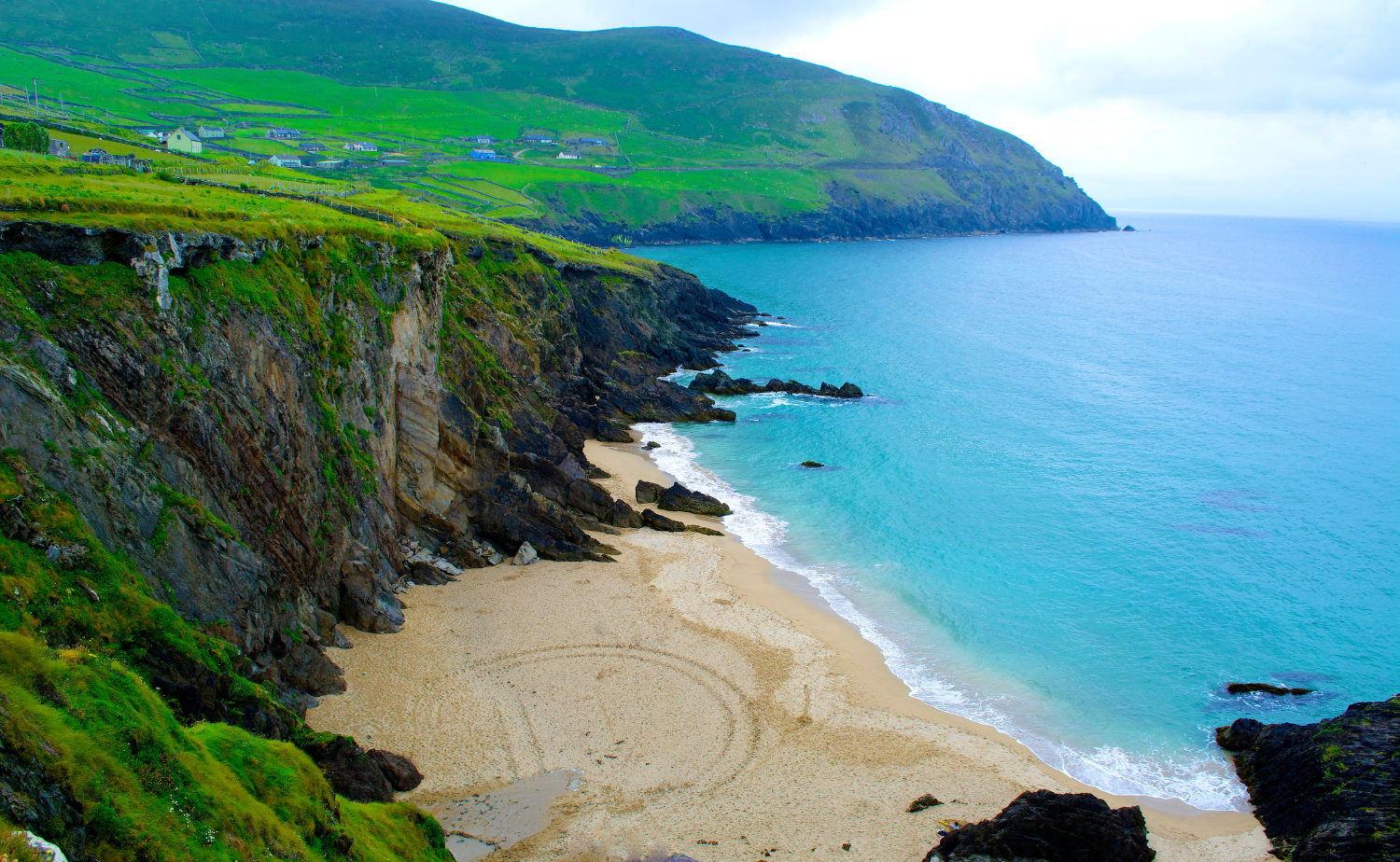 Steep coastal cliffs along Ireland’s western shoreline overlooking turquoise water and rocky beaches.