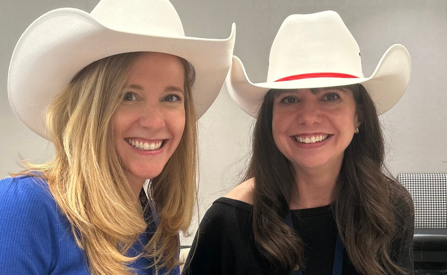 Laura and Molly smiling in white cowboy hats during Calgary’s White Hat ceremony.