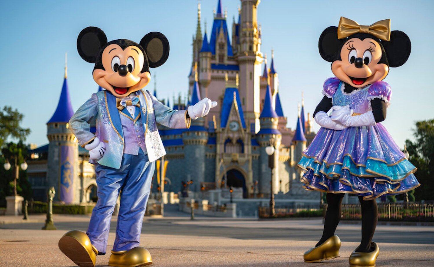 Mickey Mouse and Minnie Mouse wearing shimmering EARidescent costumes with gold accents.