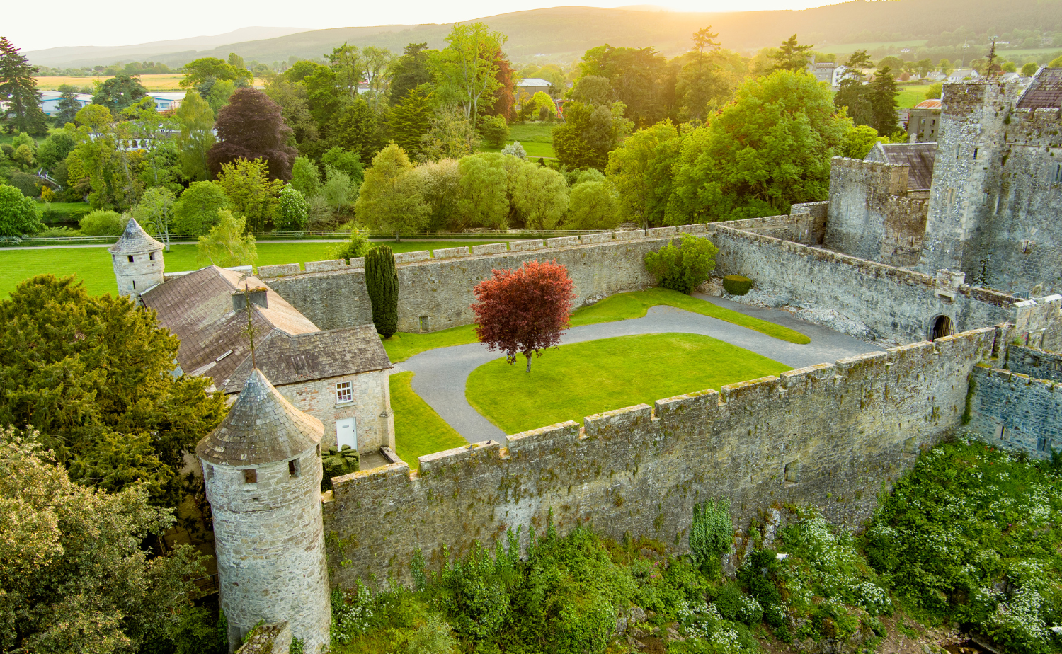 An aerial view of a historic Irish castle surrounded by green trees and countryside.