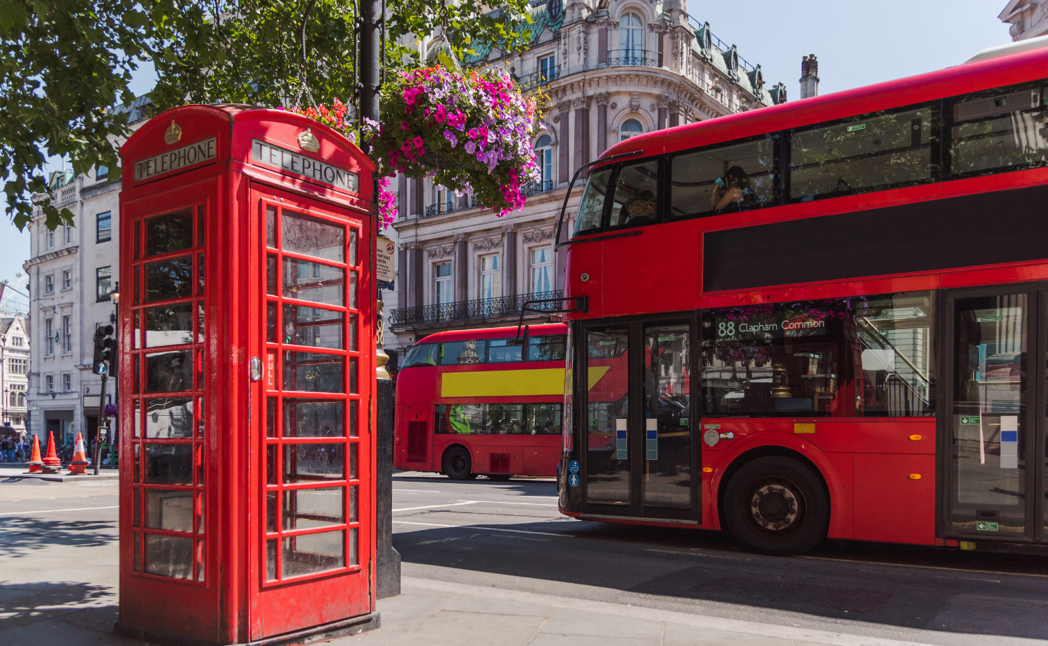 Red double decker bus and iconic telephone booth on a London street.