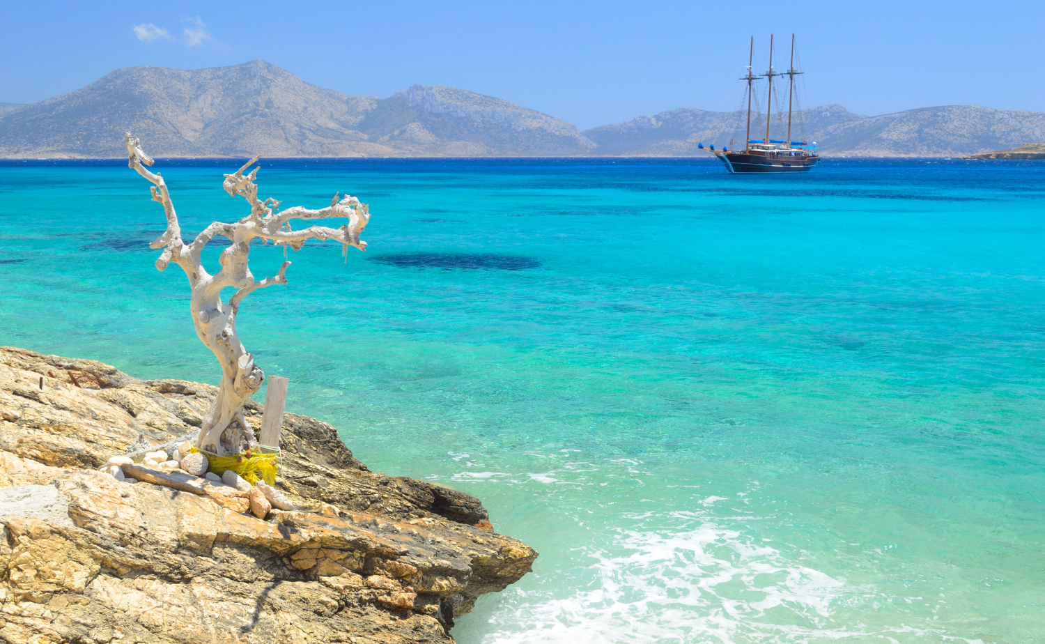 Brilliant turquoise water and a traditional sailing boat off Koufonisia in Greece’s Little Cyclades