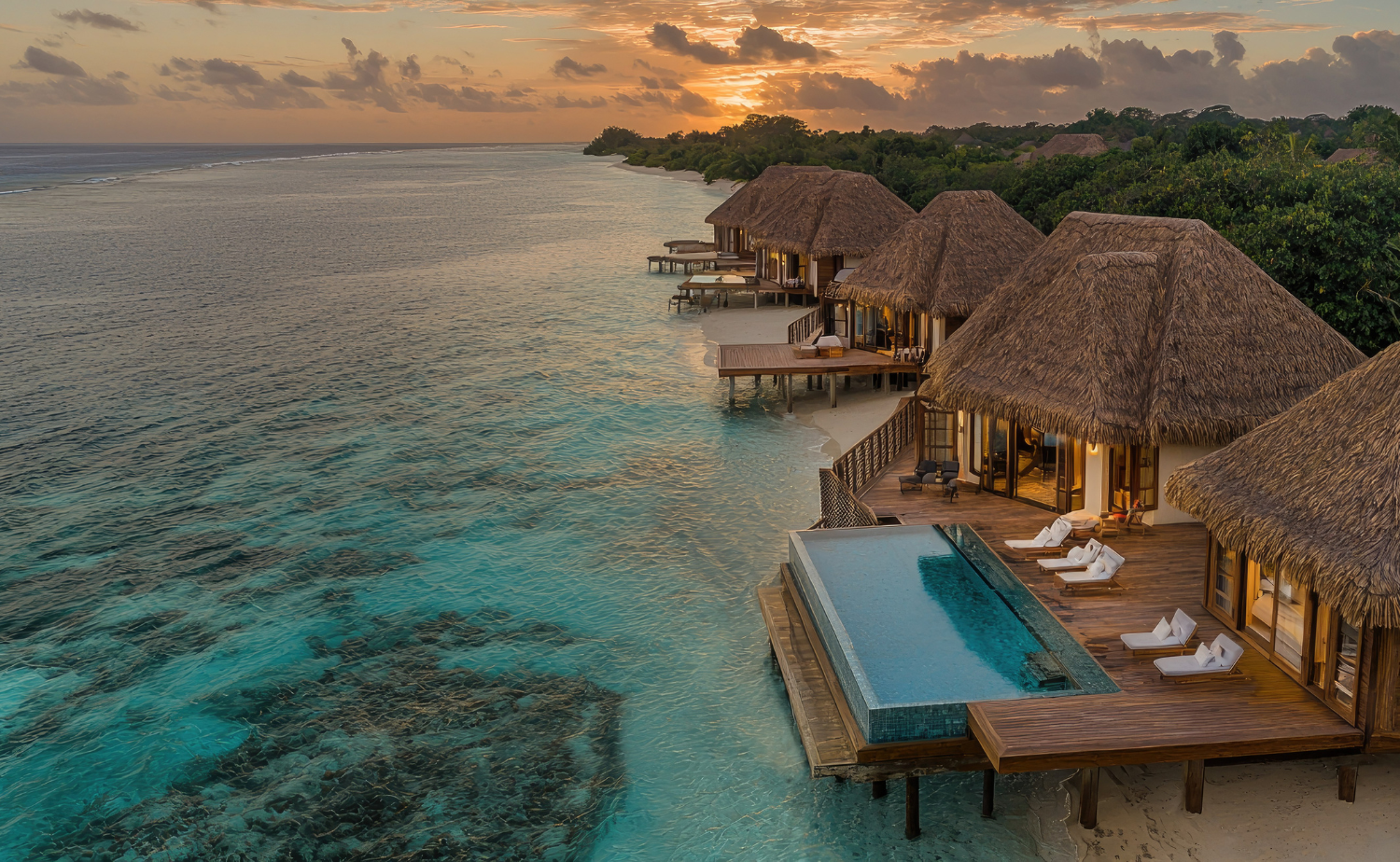 Overwater villas at sunset in Bora Bora with warm golden light reflecting across calm lagoon waters.