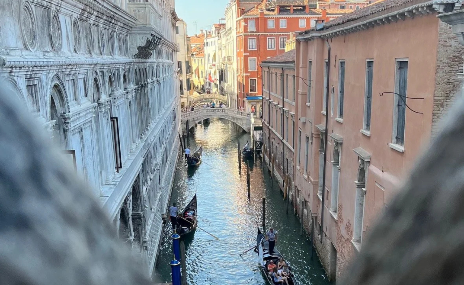 Reflections of historic buildings along a quiet canal in Venice with a small bridge overhead