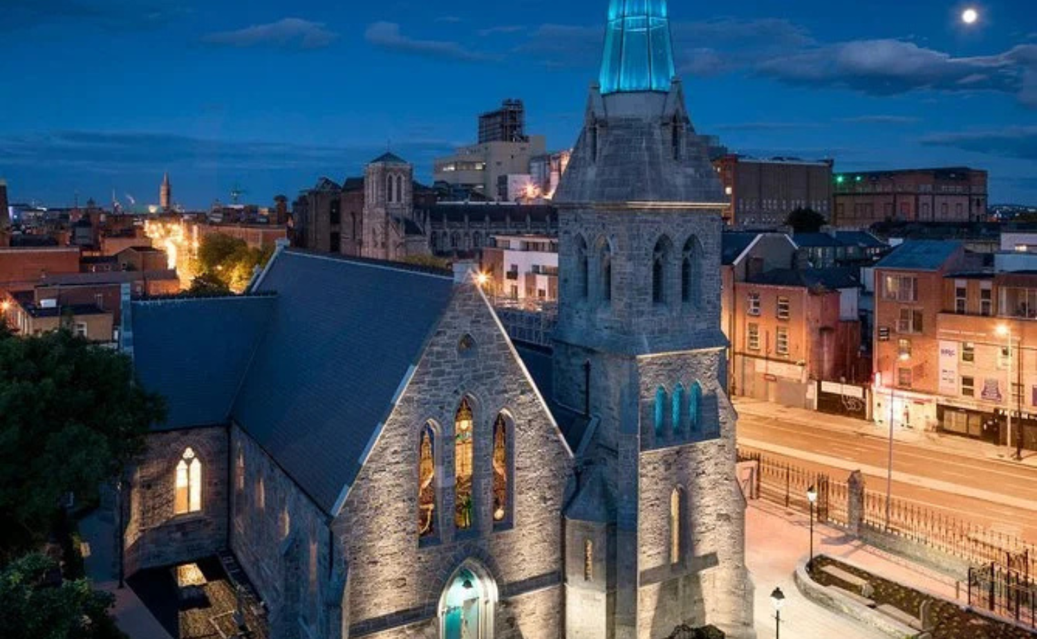 Nighttime exterior of a historic stone church in Dublin that now houses a whiskey distillery.