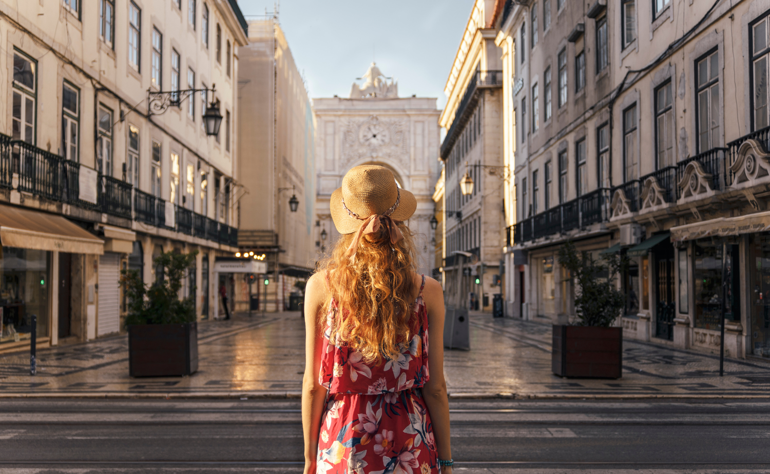 A woman standing in a quiet European street at sunrise, facing away as she admires the architecture.
