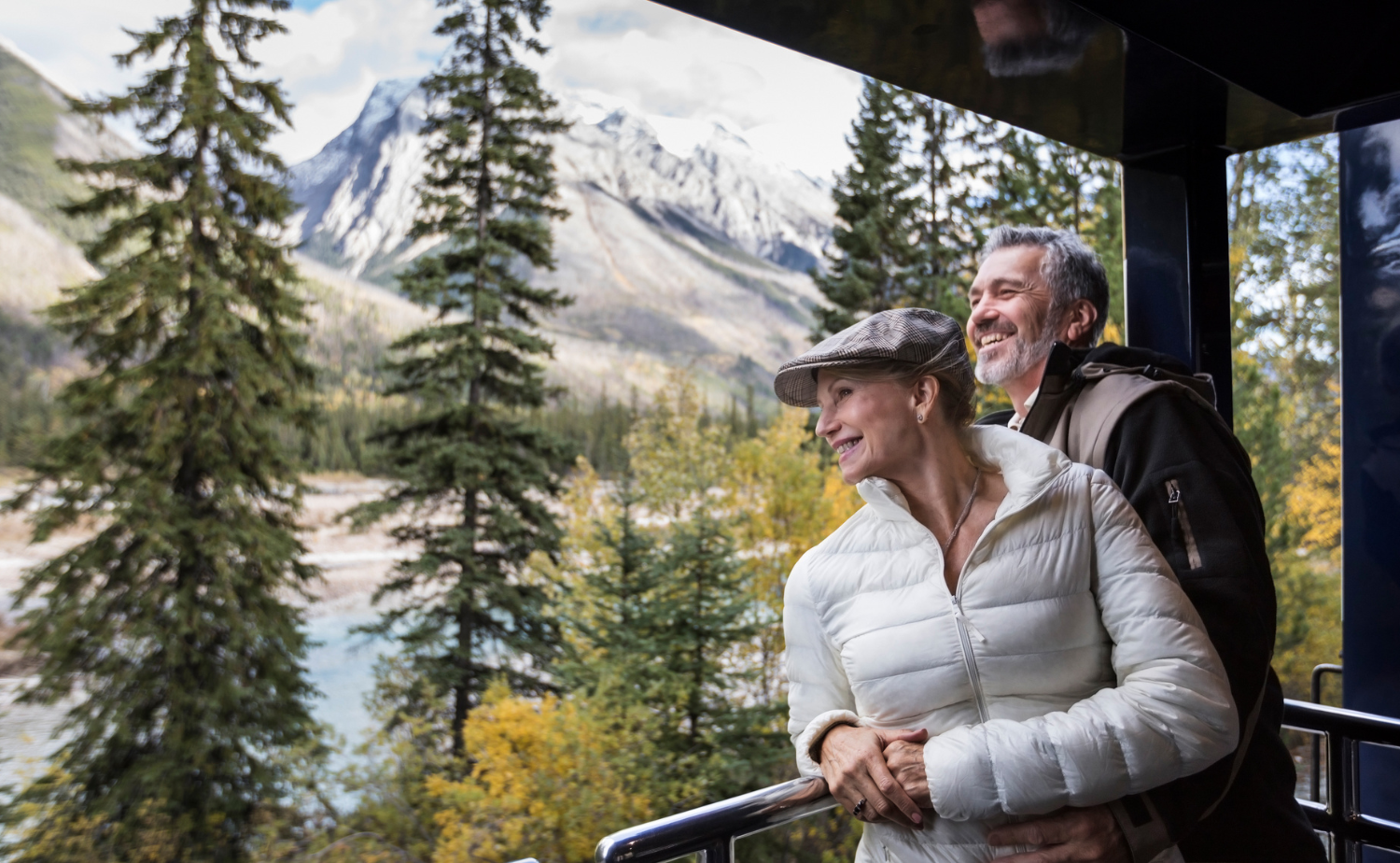 A couple enjoying mountain views from a luxury railcar traveling through the Canadian Rockies.