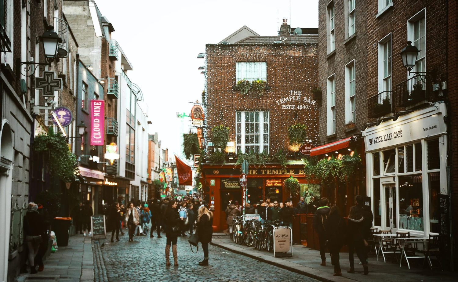 A lively street scene in Dublin’s Temple Bar area with pubs, people, and cobblestone streets.