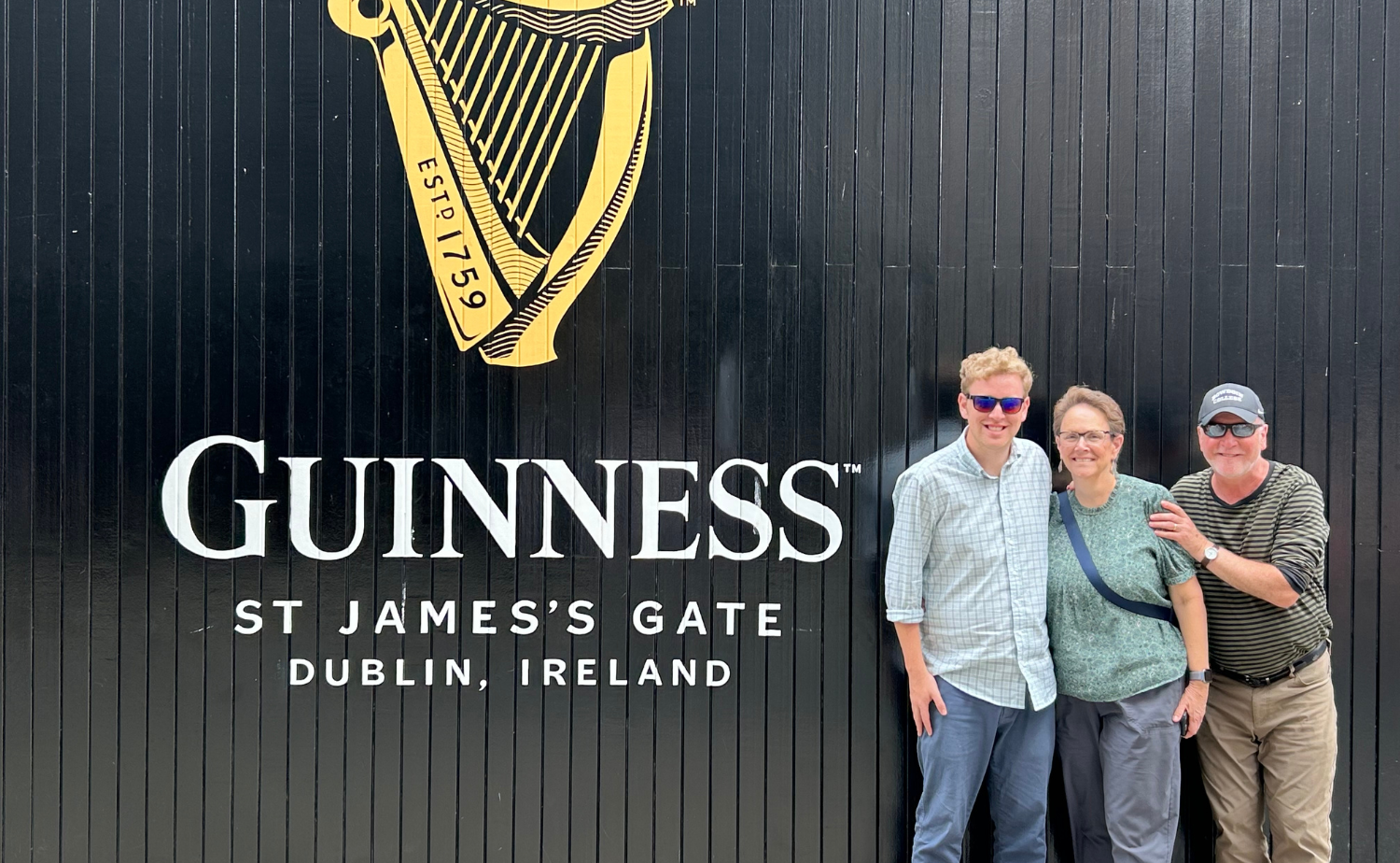 Family standing in front of the Guinness St. James’s Gate sign in Dublin, Ireland.